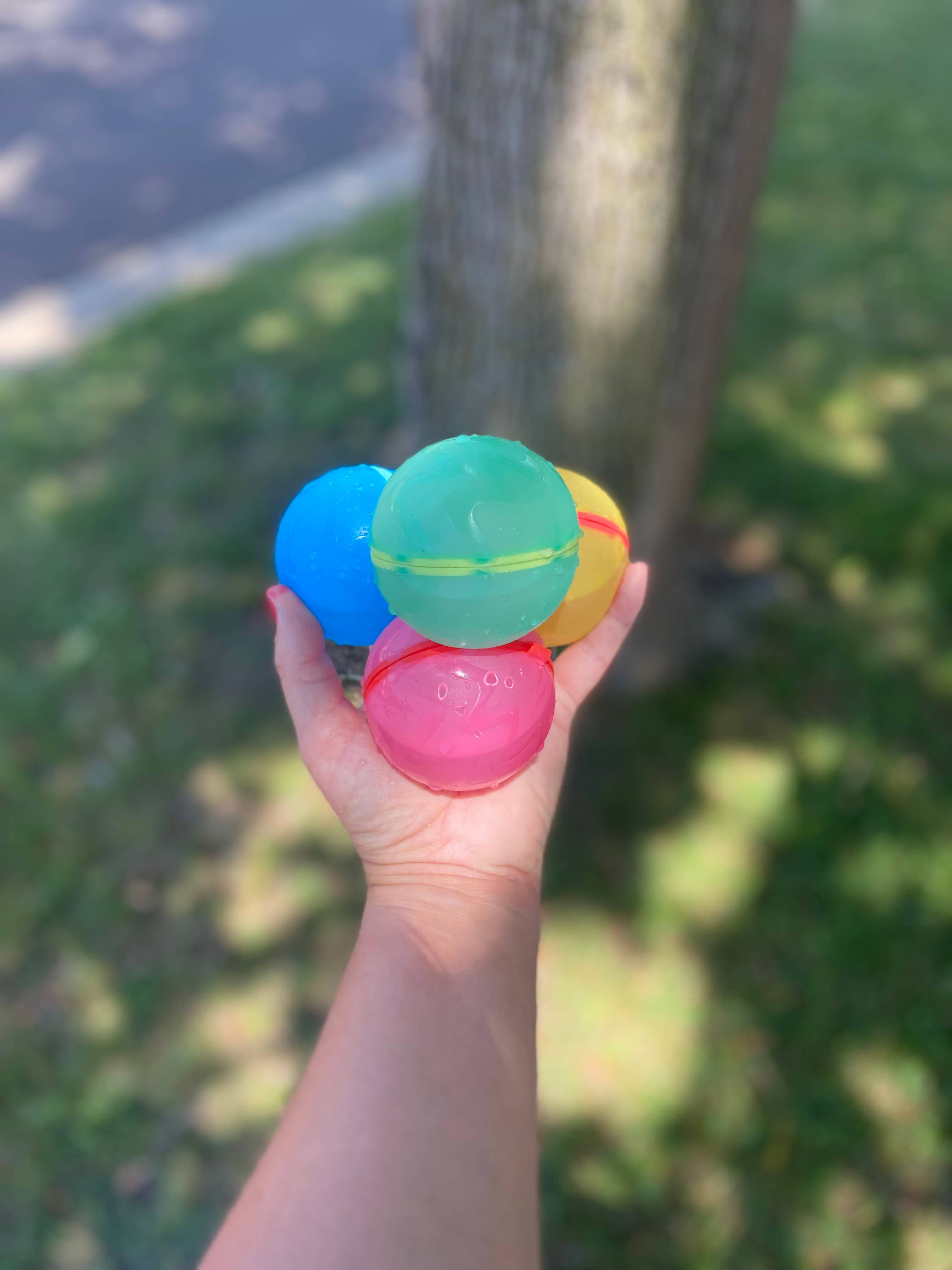 Colorful reusable water balloons held in a hand with a blurred natural background