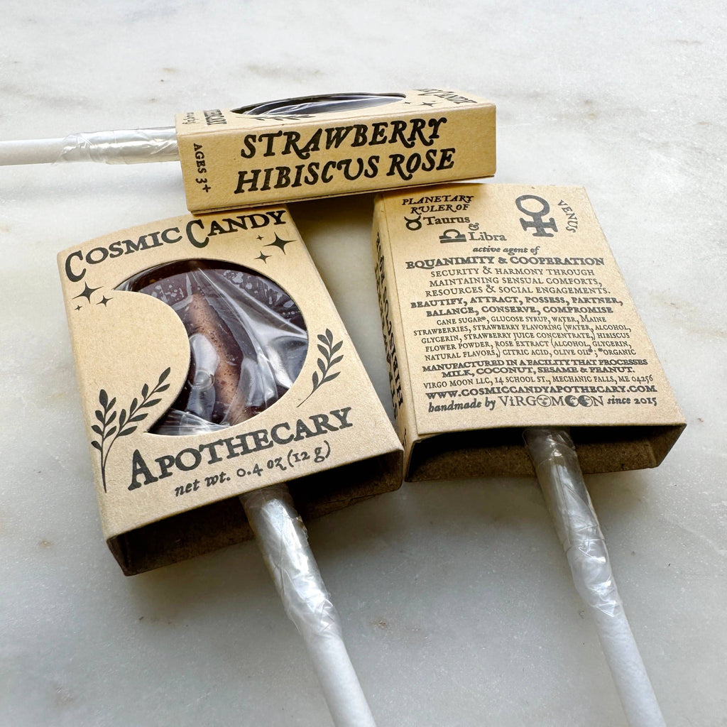 Two Cosmic Candy Apothecary lollipops in cardboard packaging on a light background