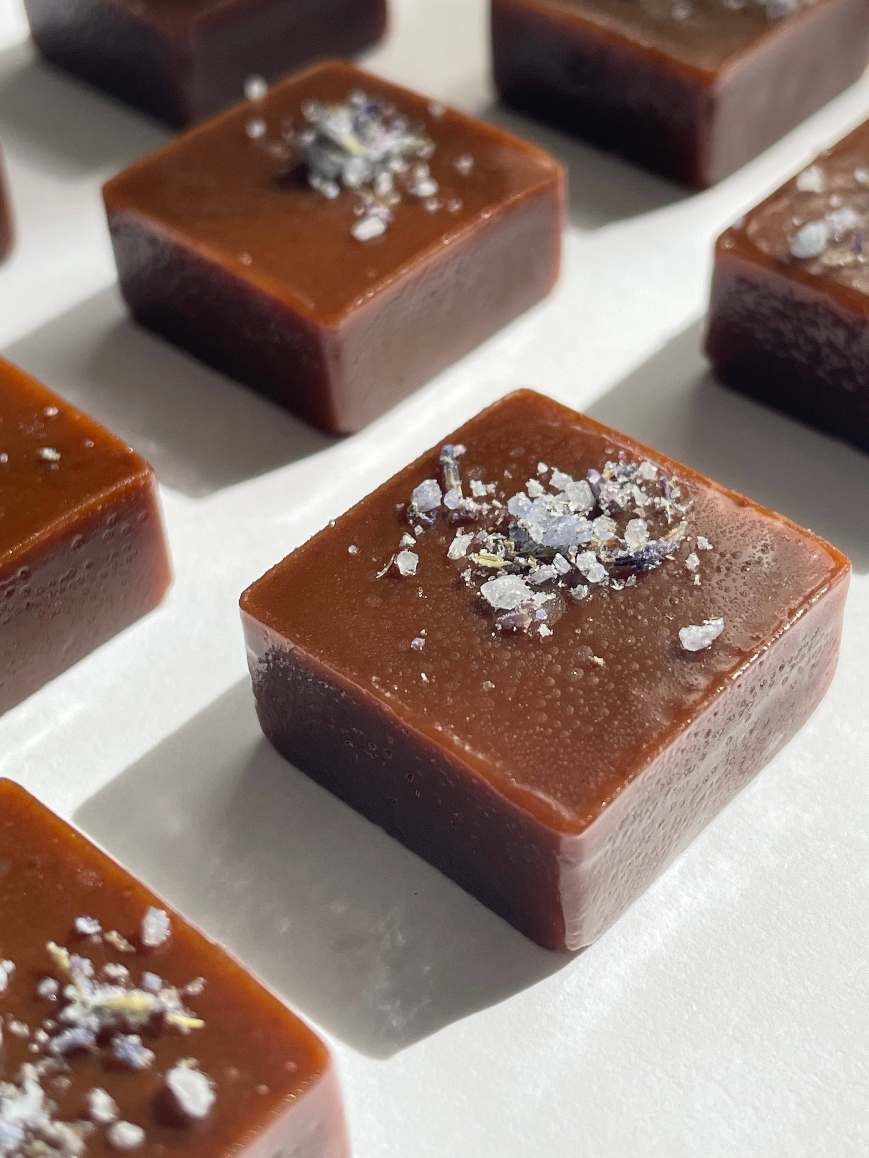 Square chocolate candies with sea salt on a white surface