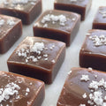 Caramel pieces with salt flakes on a white surface