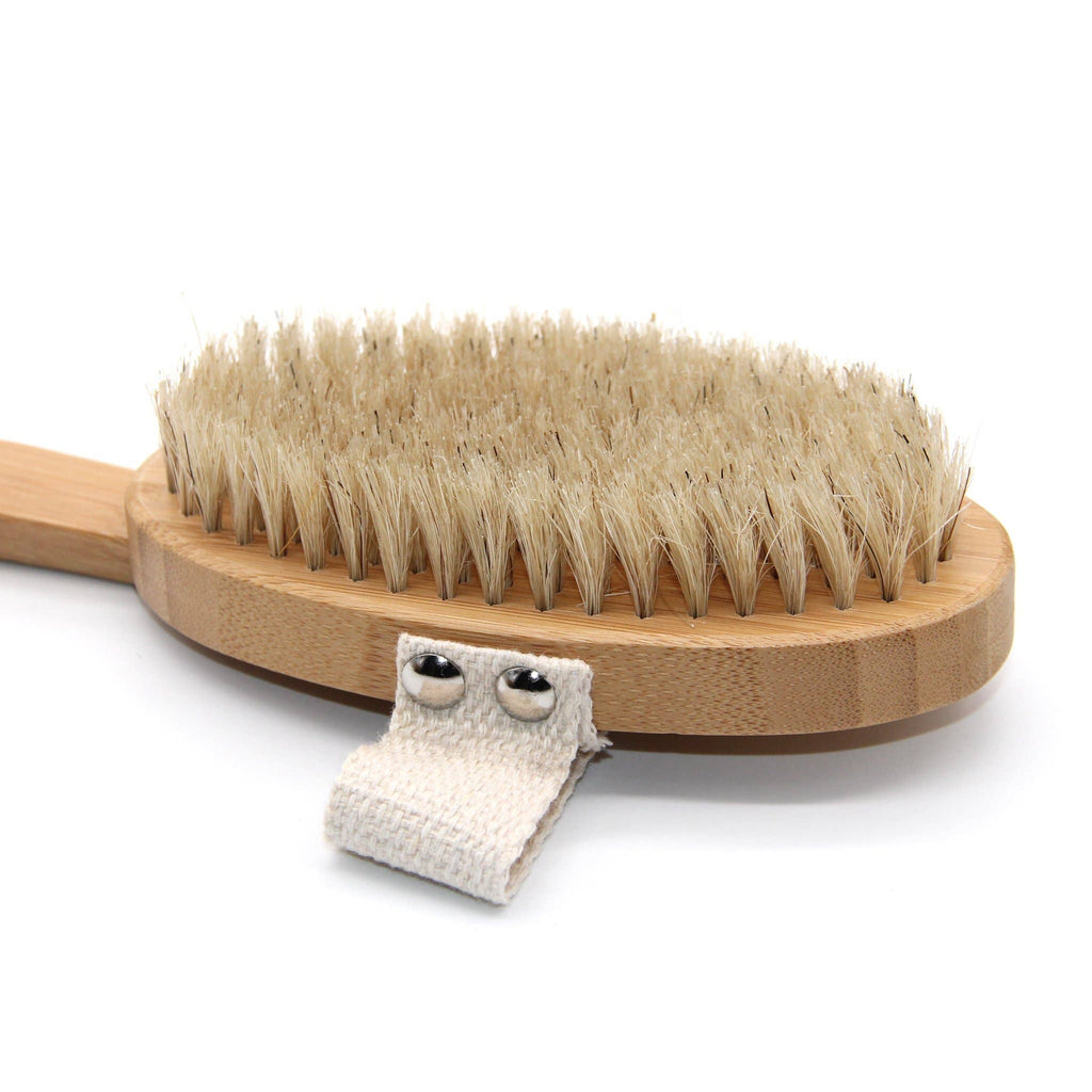 Wooden brush with natural bristles and a small white towel on a white background