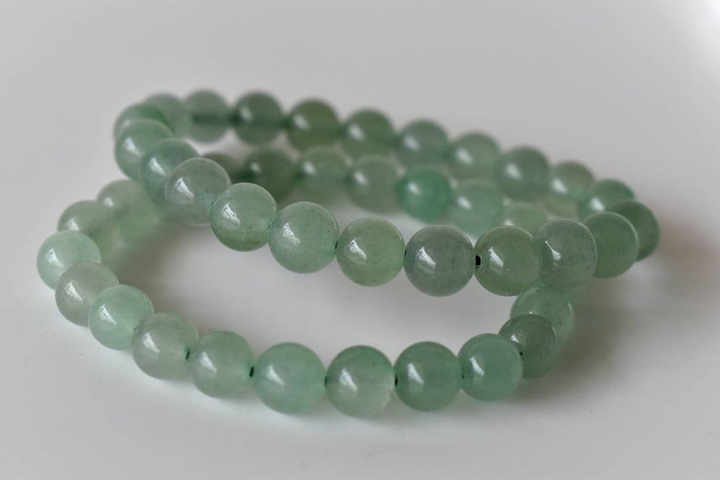 Two green beaded bracelets on a white background