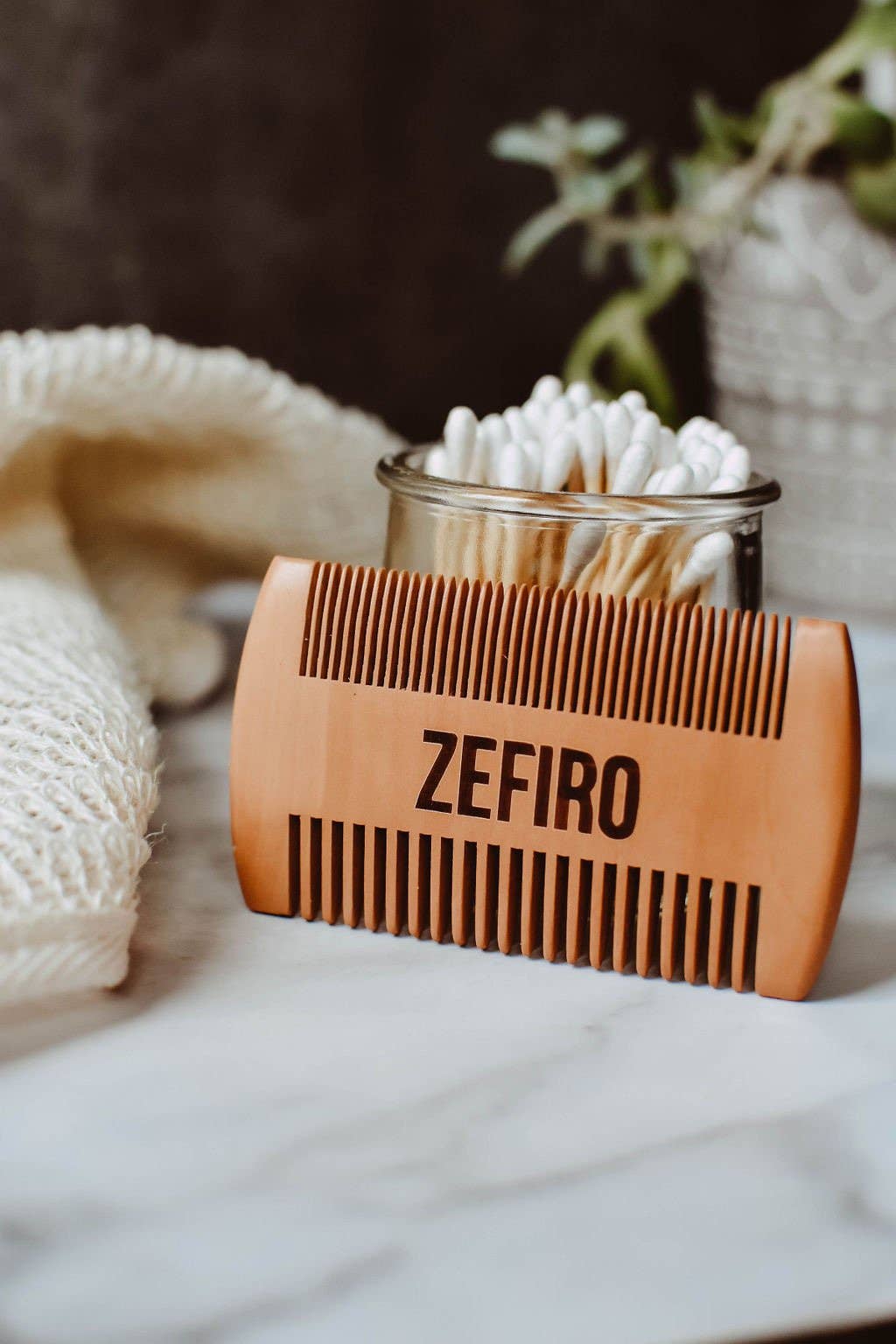 Wooden comb with 'Zefiro' branding on a marble surface with a blurred background