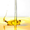 Close-up of olive oil being poured with a white background
