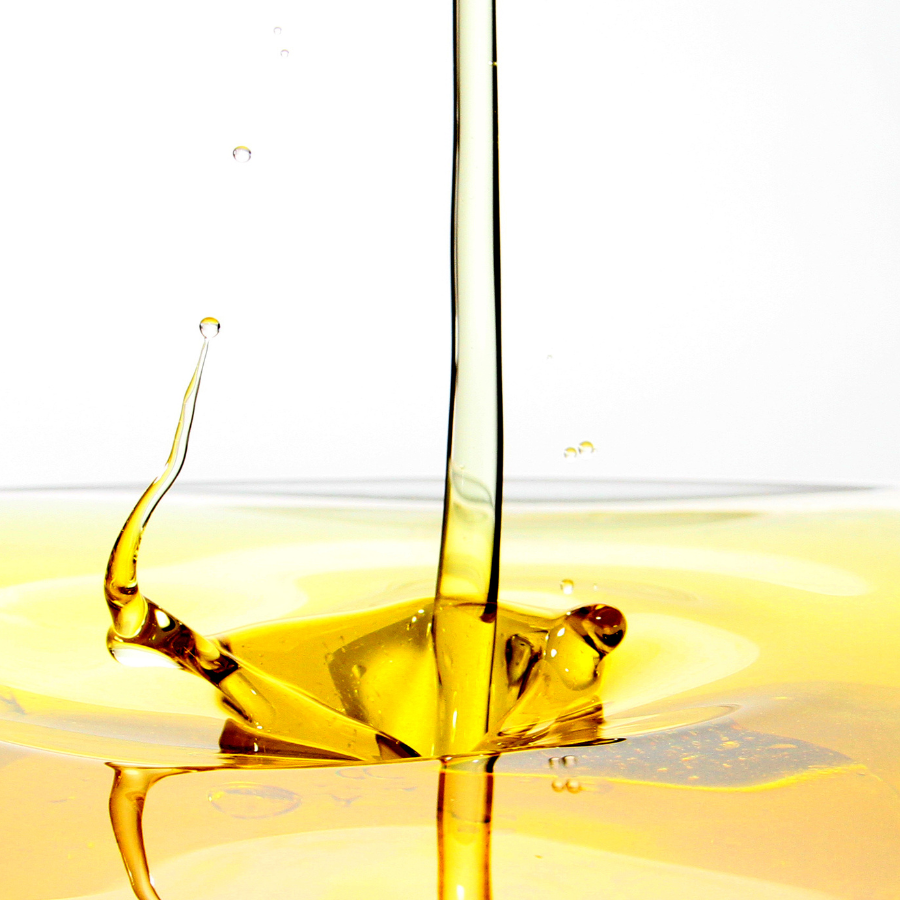 Close-up of olive oil being poured with a white background