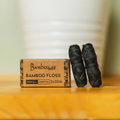 Two rolls of Bamboo Switch bamboo floss and their packaging on a wooden surface.