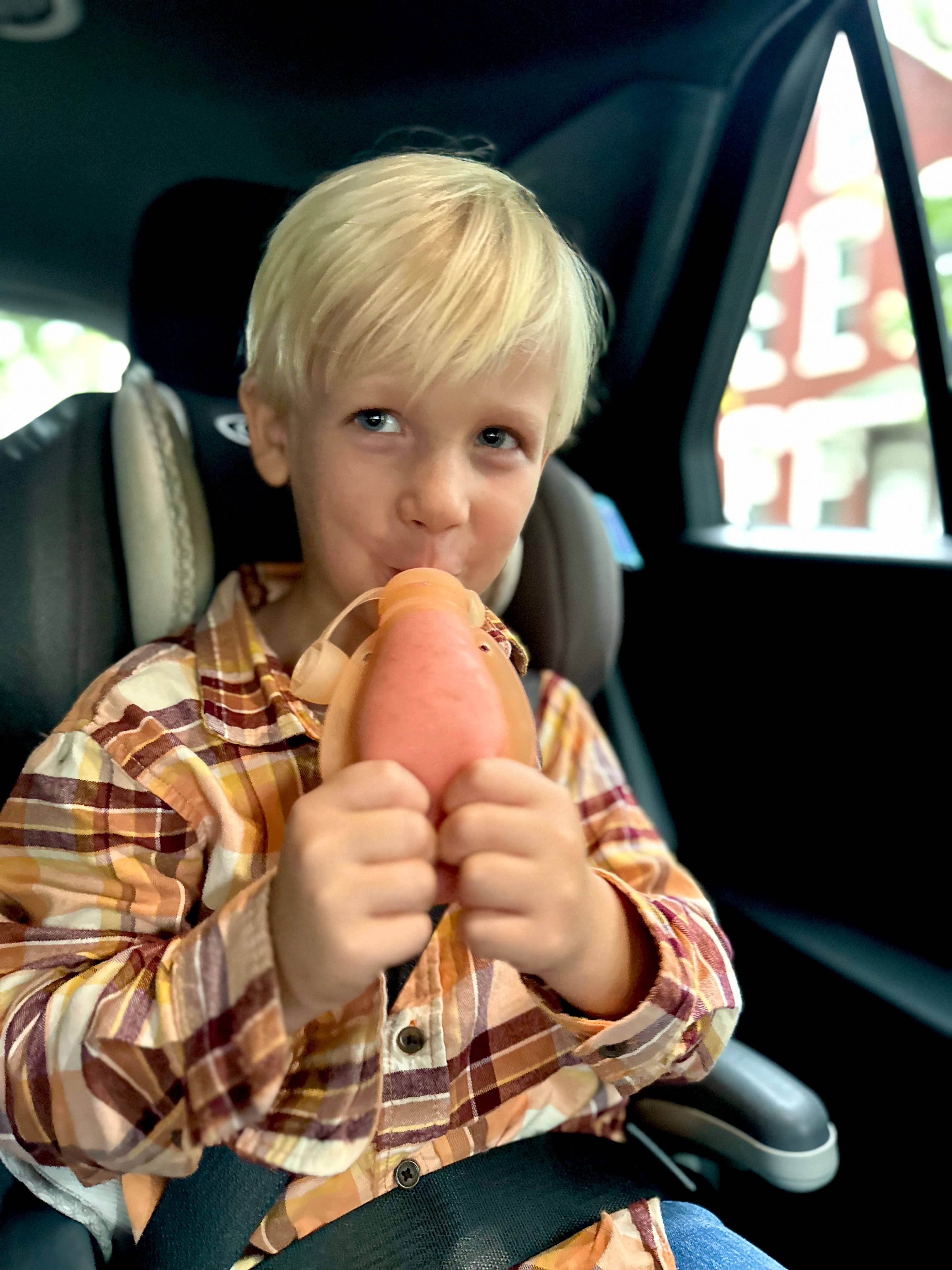 Child holding a squeeze pouch inside a car