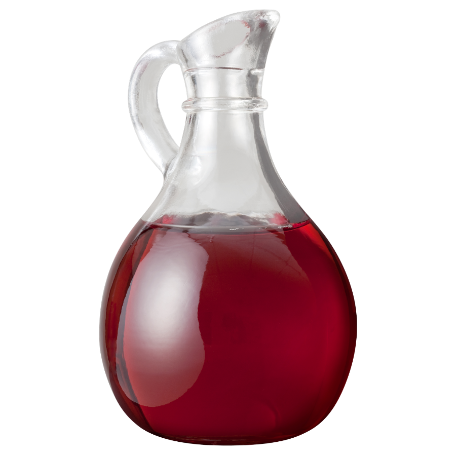 Clear glass pitcher filled with red wine vinegar on a white background