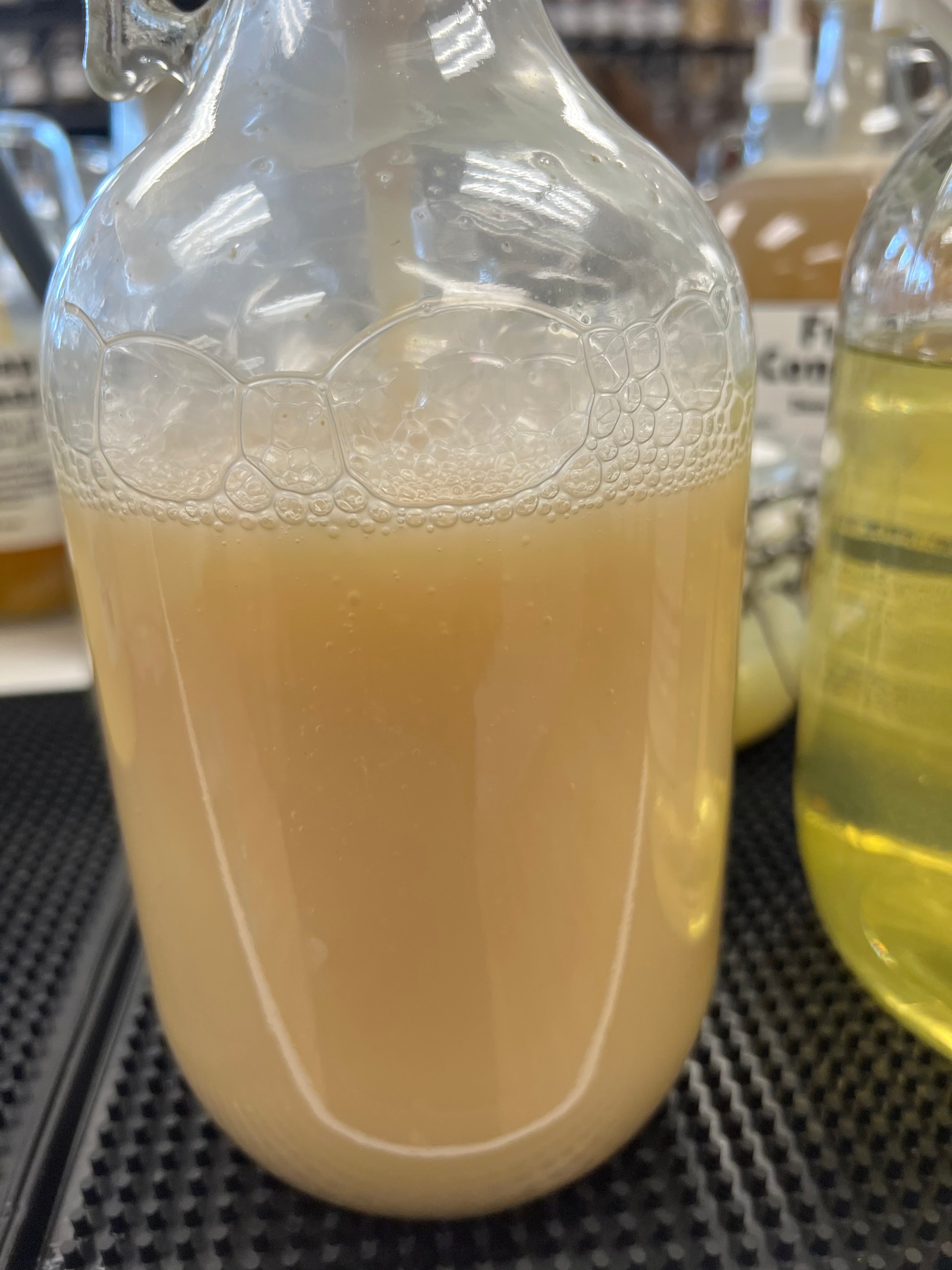 Close-up of a glass with a creamy liquid and a beige cap, blurred background