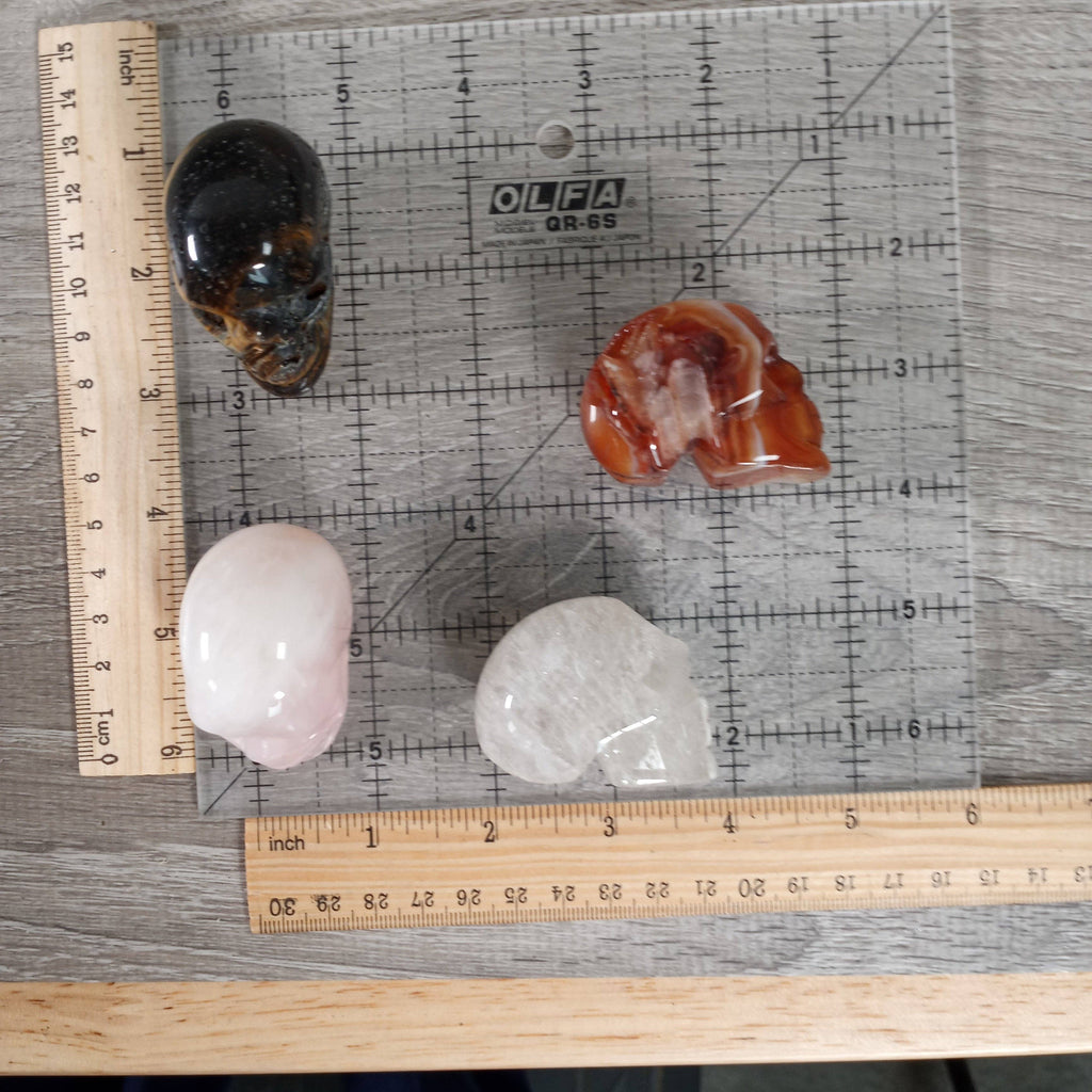 Four crystals on a gray surface with an OLFA ruler for scale.