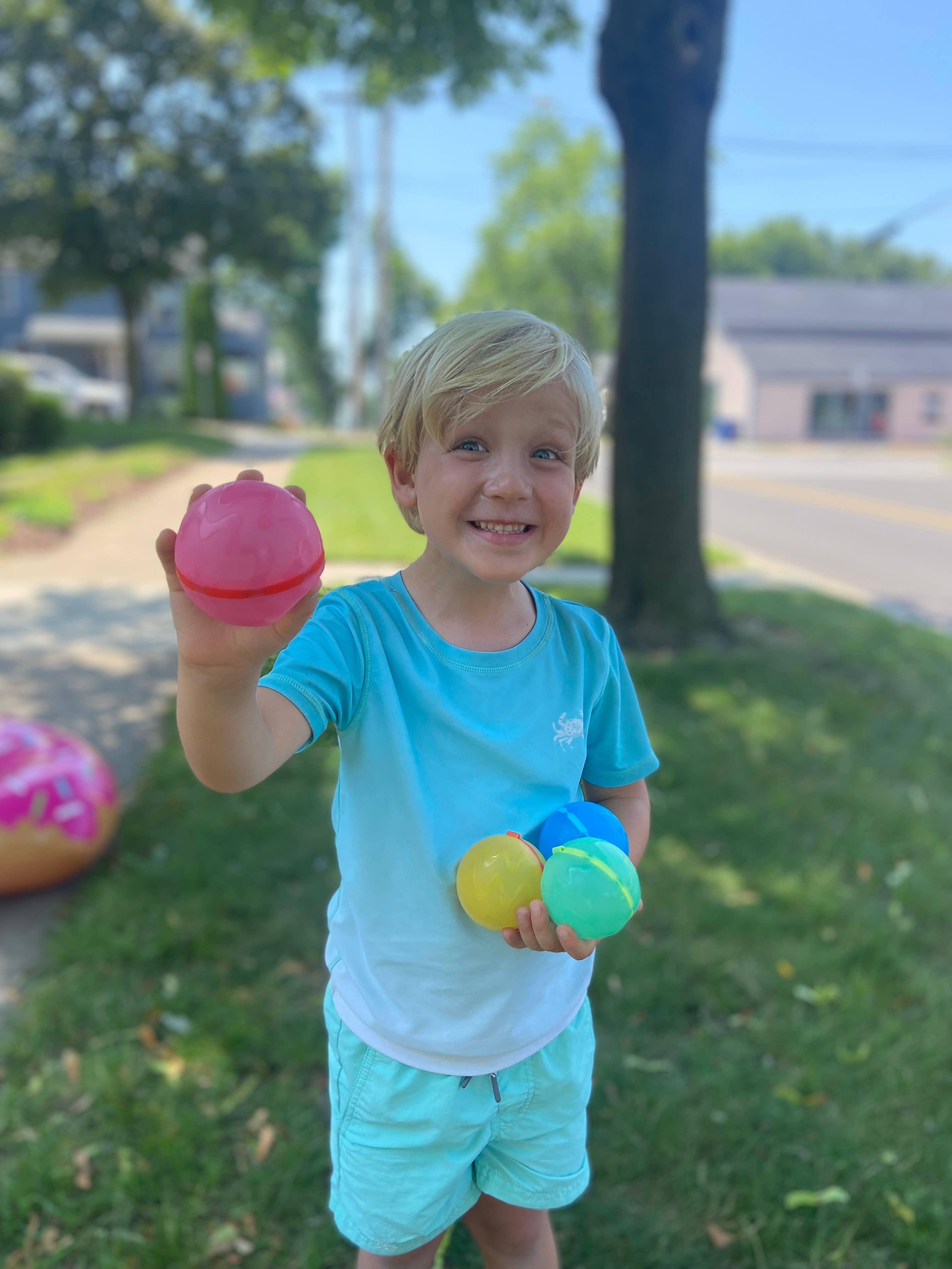 Child holding colorful reusable water balloons outdoors on a sunny day