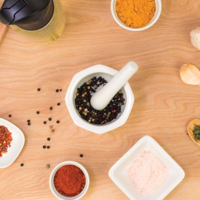Spices and a mortar and pestle on a wooden surface