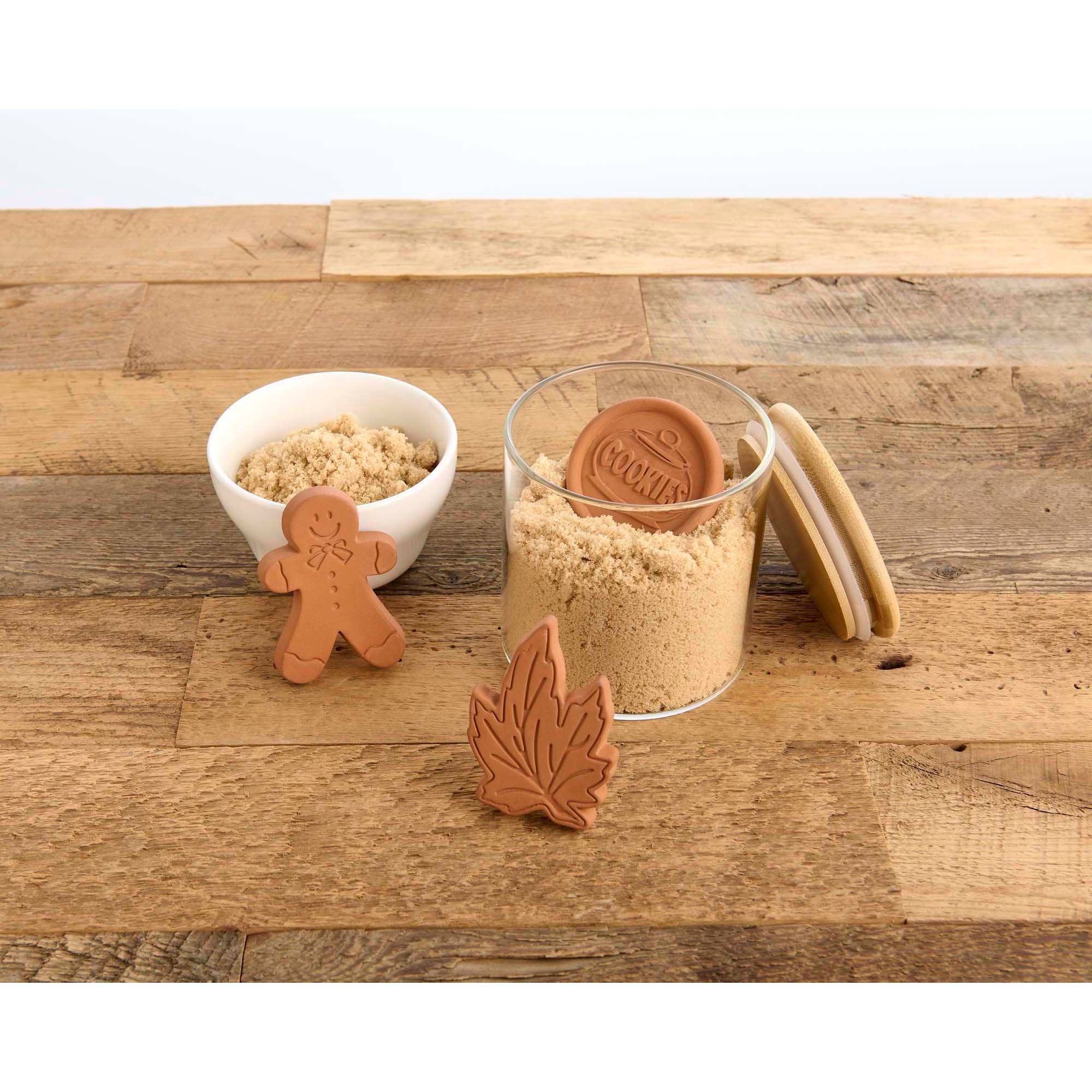 Cookie cutters shaped like a gingerbread man, leaf, and other designs on a wooden surface.