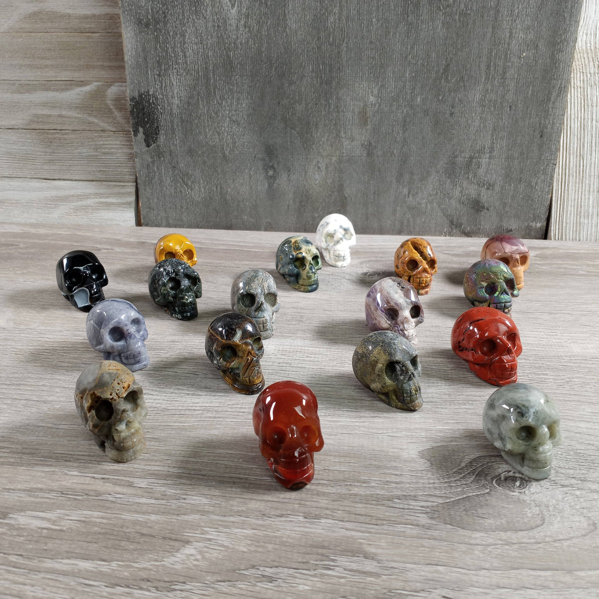 Assorted colorful stone skulls on a wooden surface with a neutral background