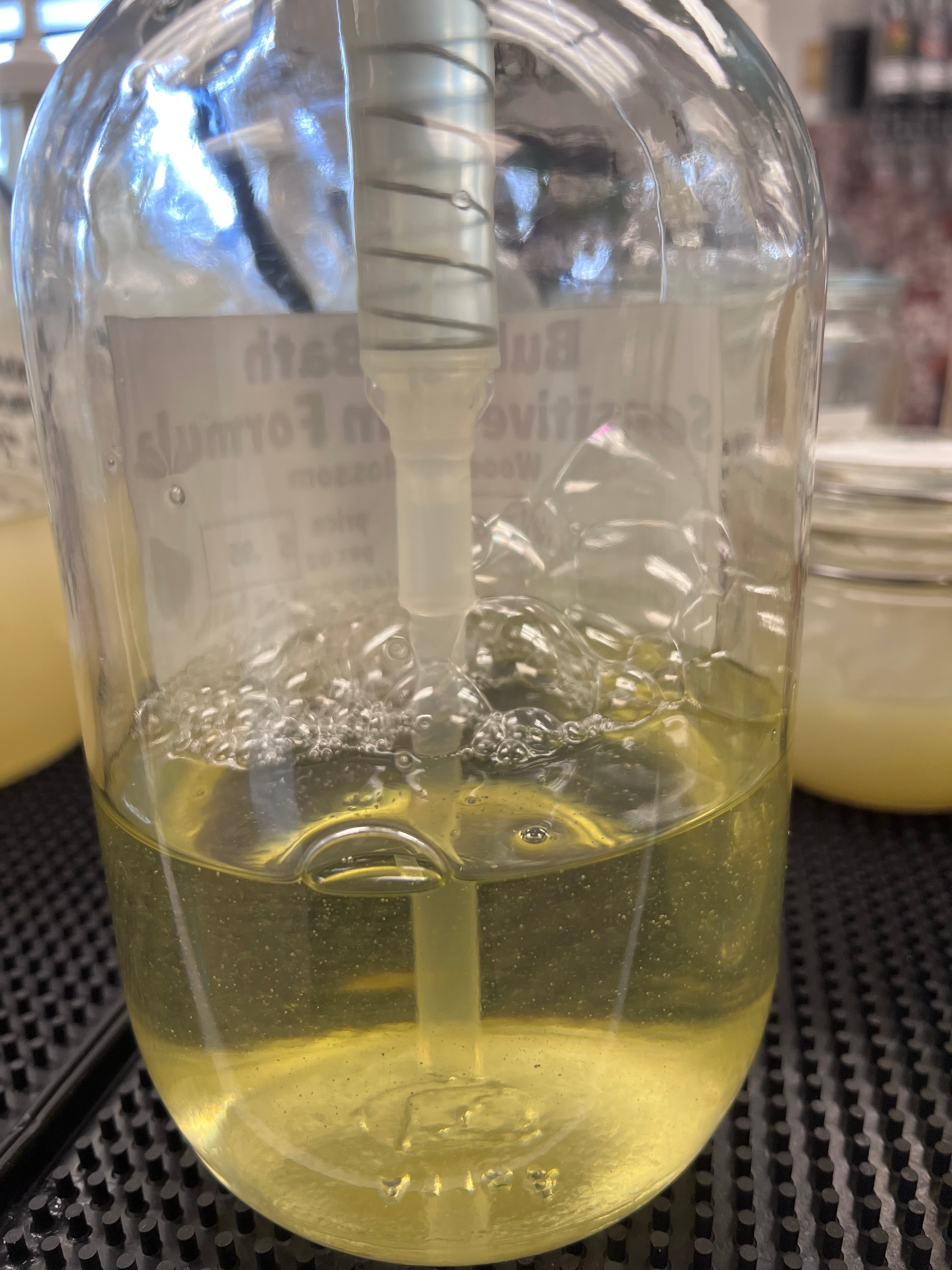 Close-up of a clear glass bottle with a yellow colored soap on a blurred background