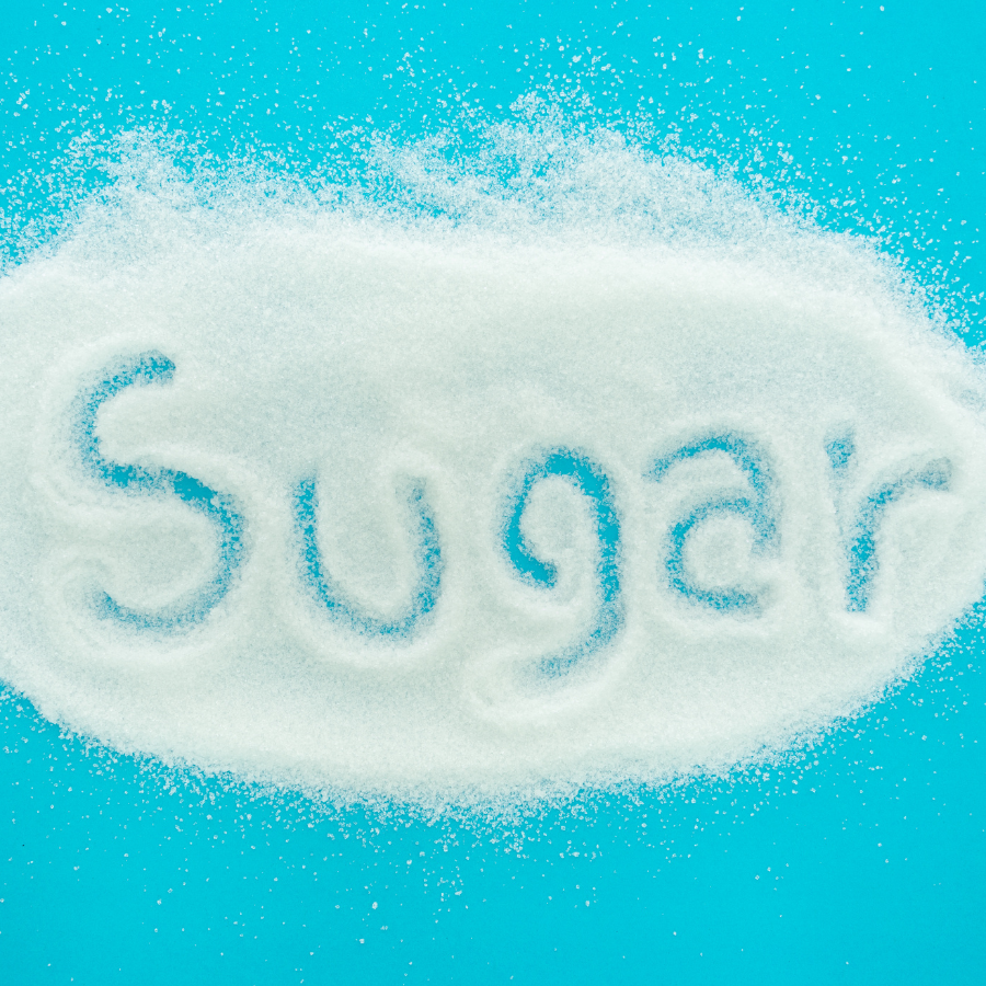 Sugar text written on a pile of sugar crystals against a blue background