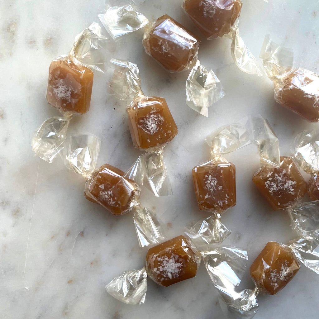 Caramel candies in clear wrappers on a marble surface