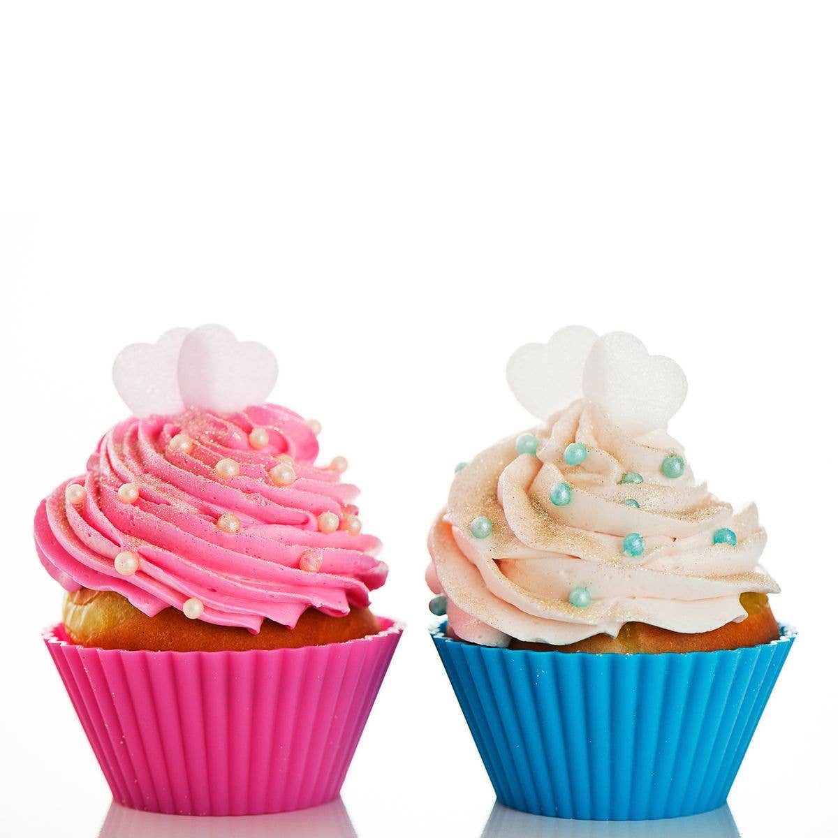Two cupcakes with pink and blue silicone liners on a white background