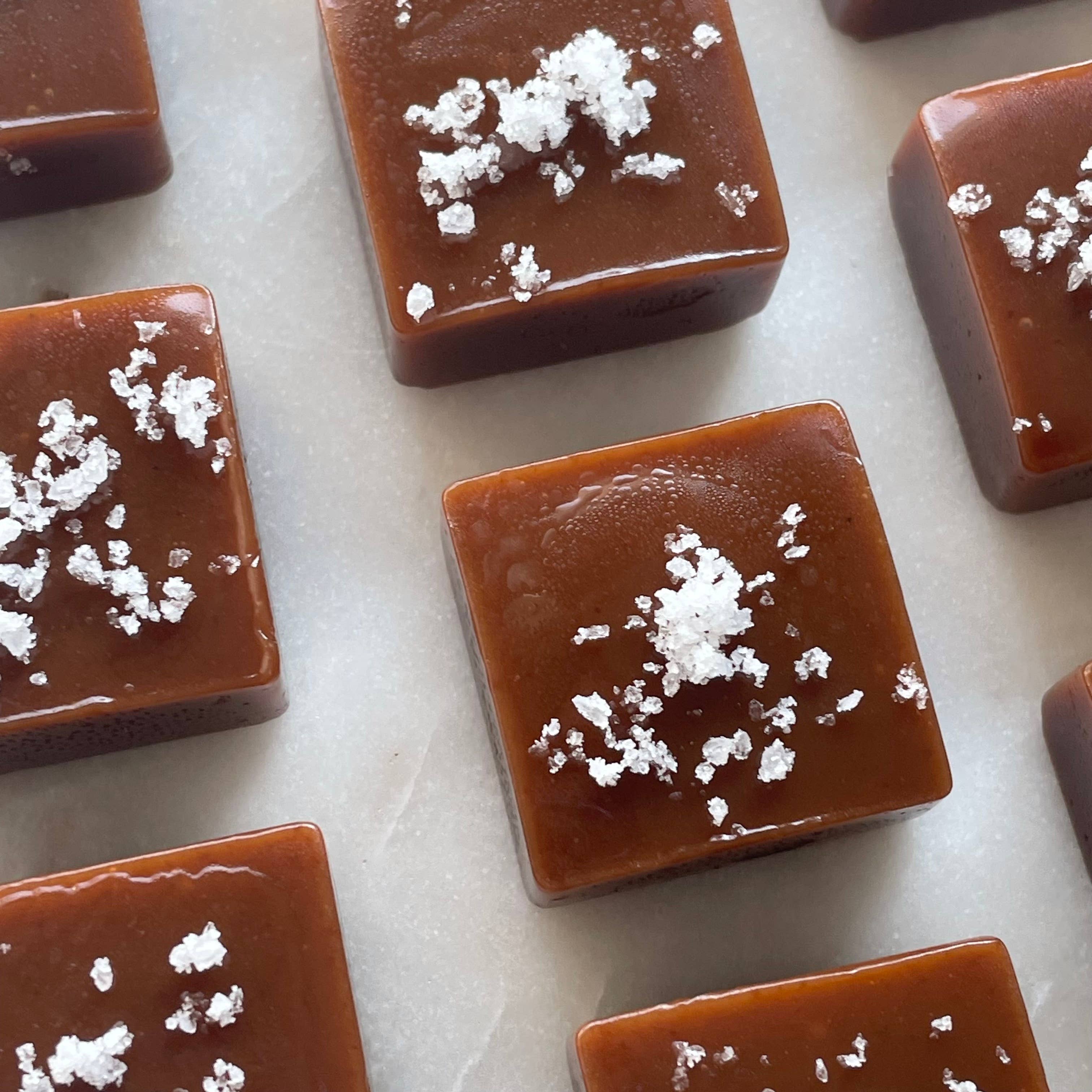 Square pieces of caramel with white crumb toppings arranged on a light surface.
