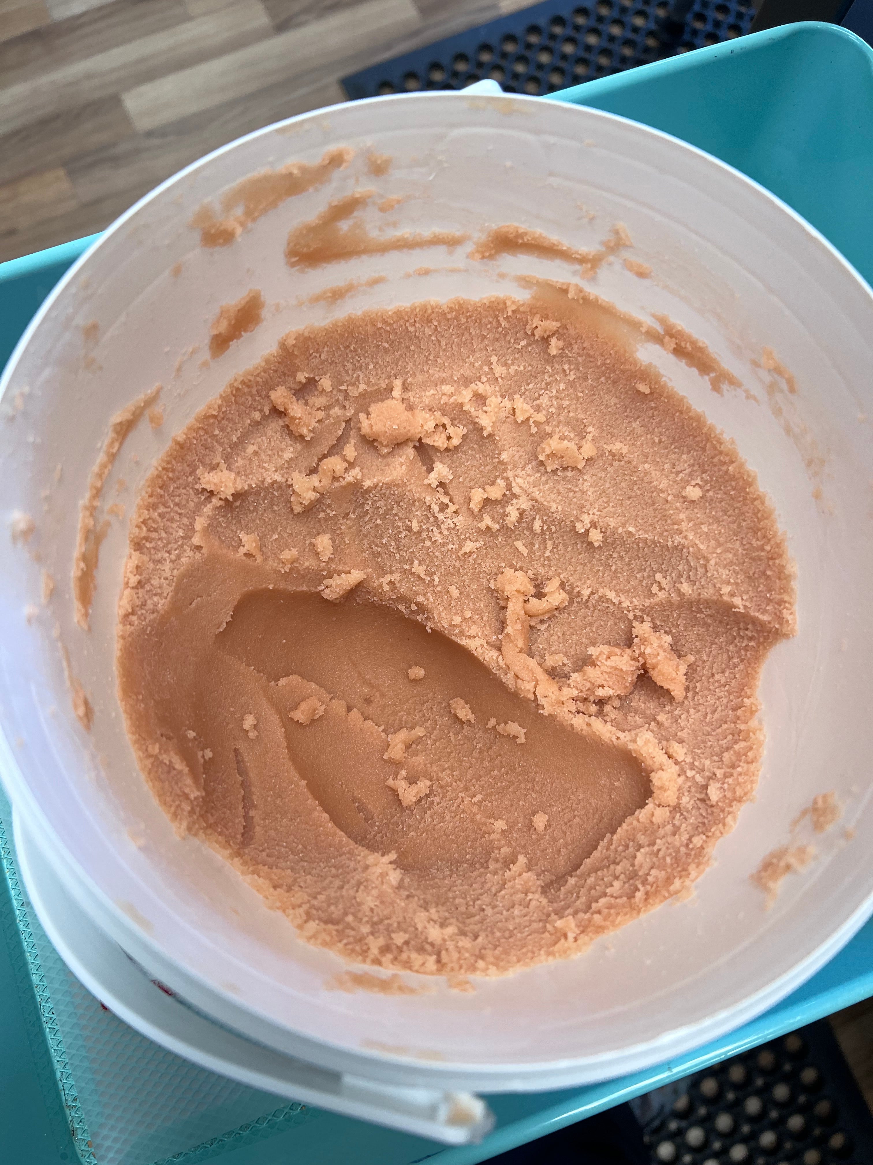 Peach colored sugar scrub in a white container on a blue tray