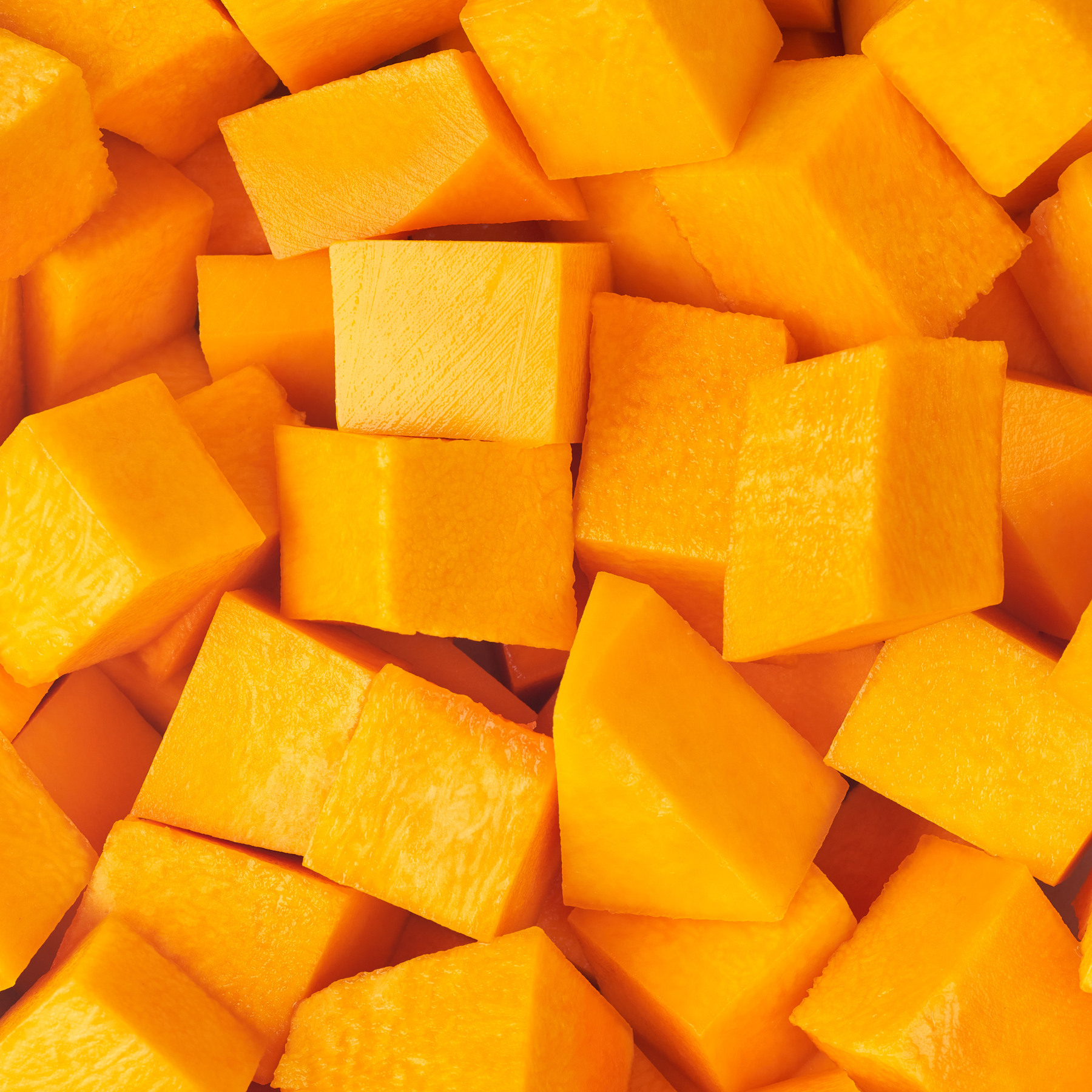Close-up of cubed orange-yellow butternut squash, filling the frame.