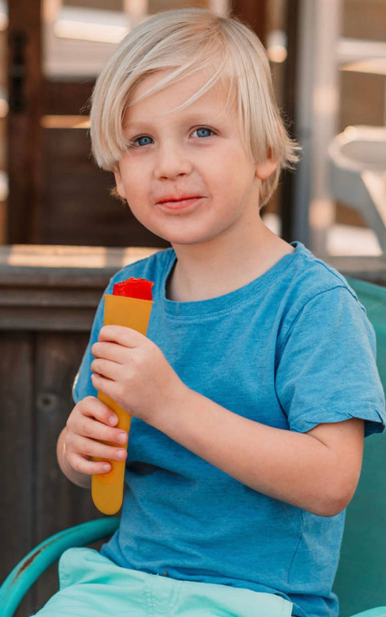Child holding a Yellow push pop outside