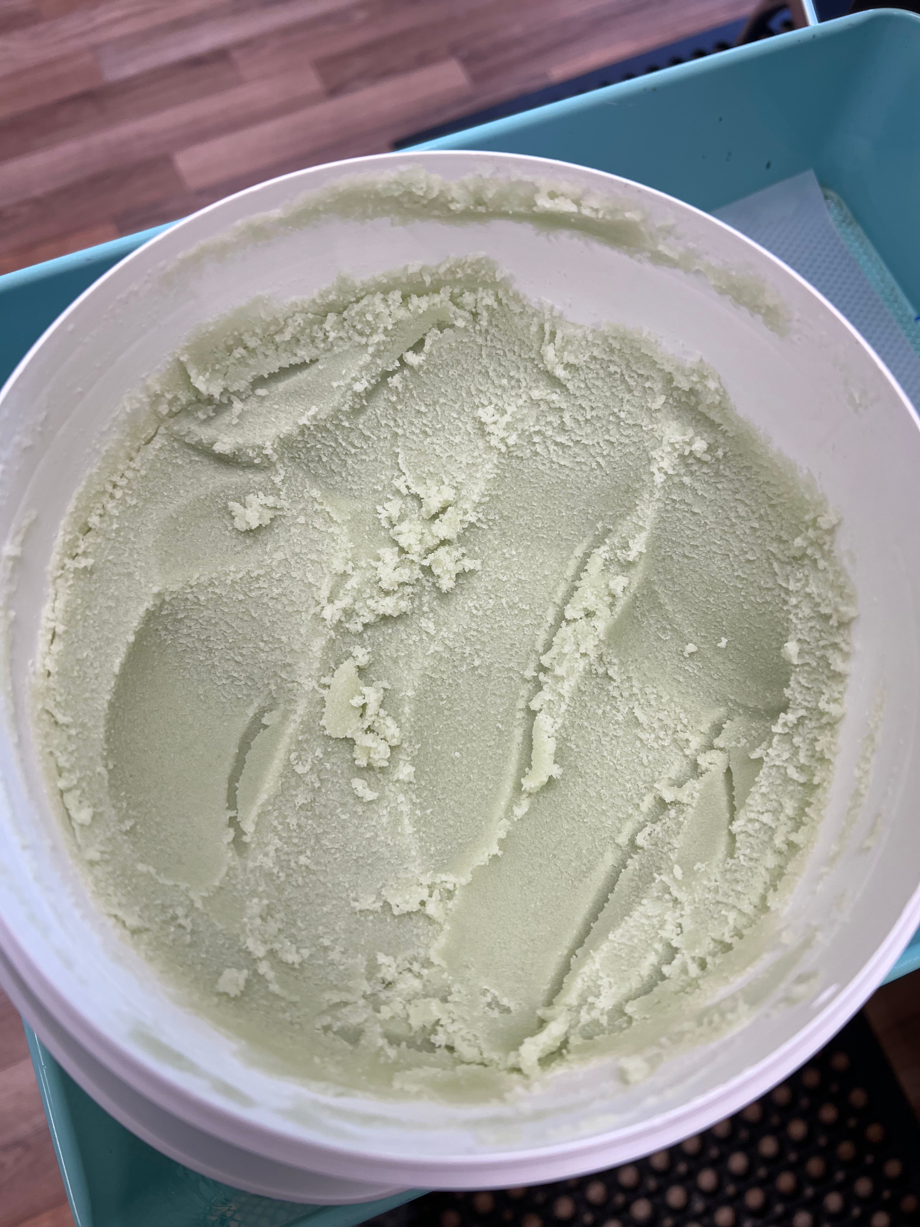 Green sugar scrub in a white container on a blue tray
