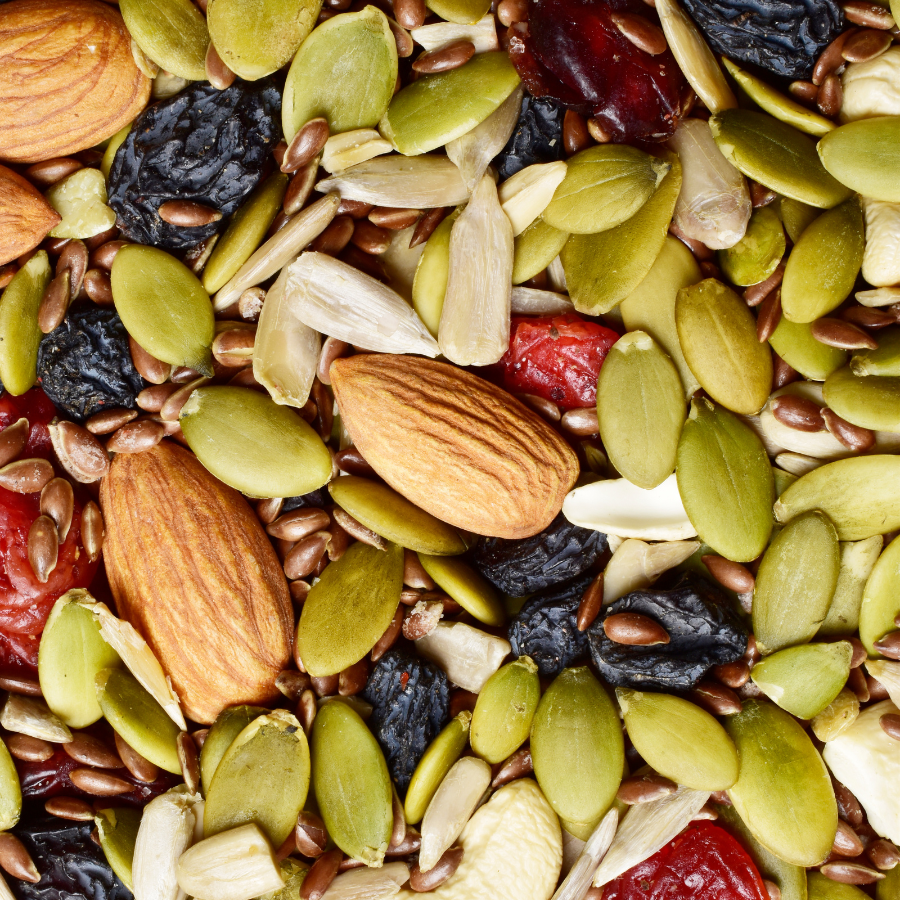 Assorted nuts, seeds, and dried fruits including almonds, pumpkin seeds, and raisins.