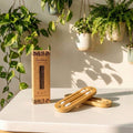 Bamboo silicone earbud holder with packaging on a table with plants in the background