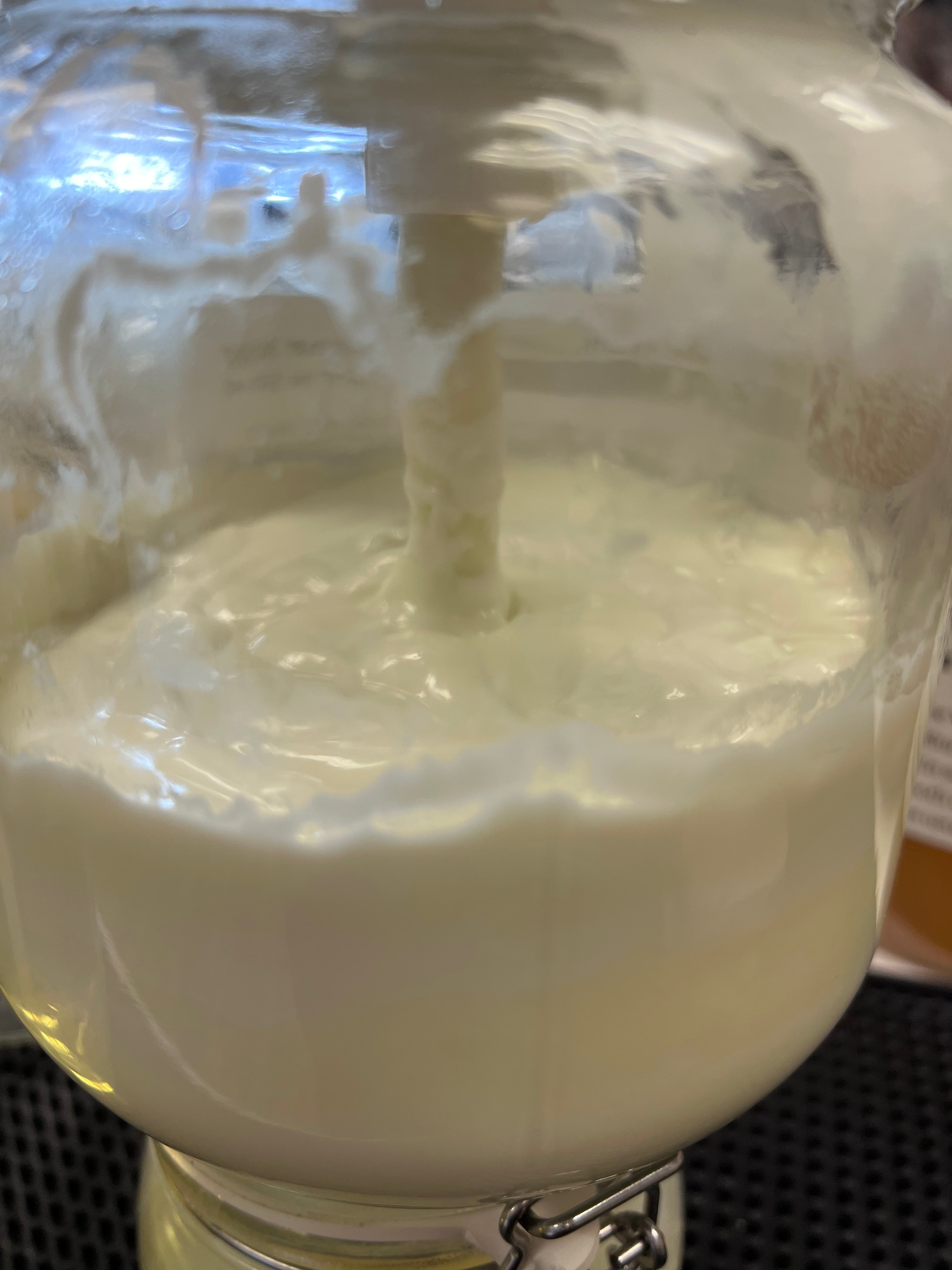 Close-up of a glass pump jar with white lotion in it on a black countertop 