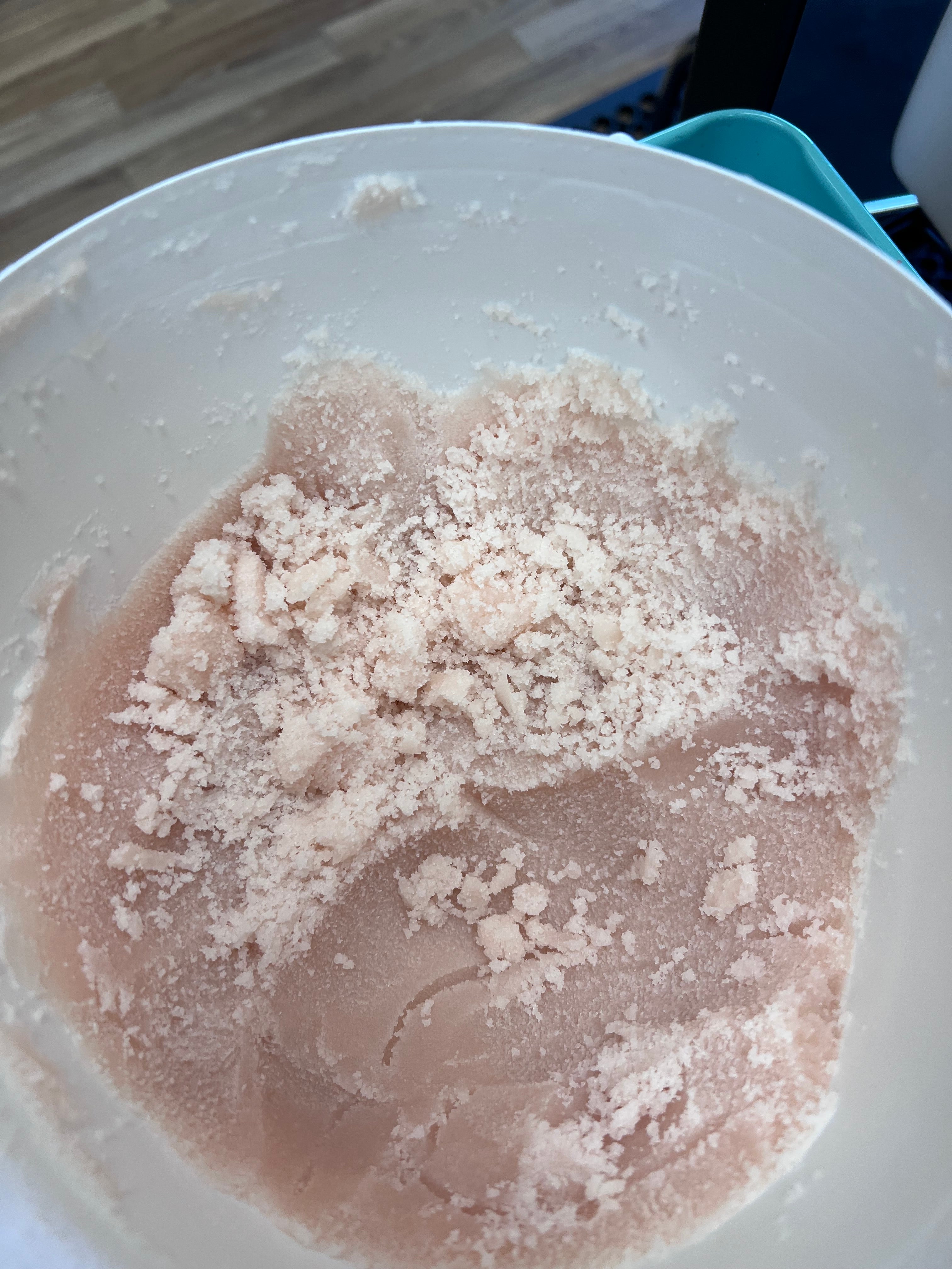 Pink sugar scrub in a white tub .