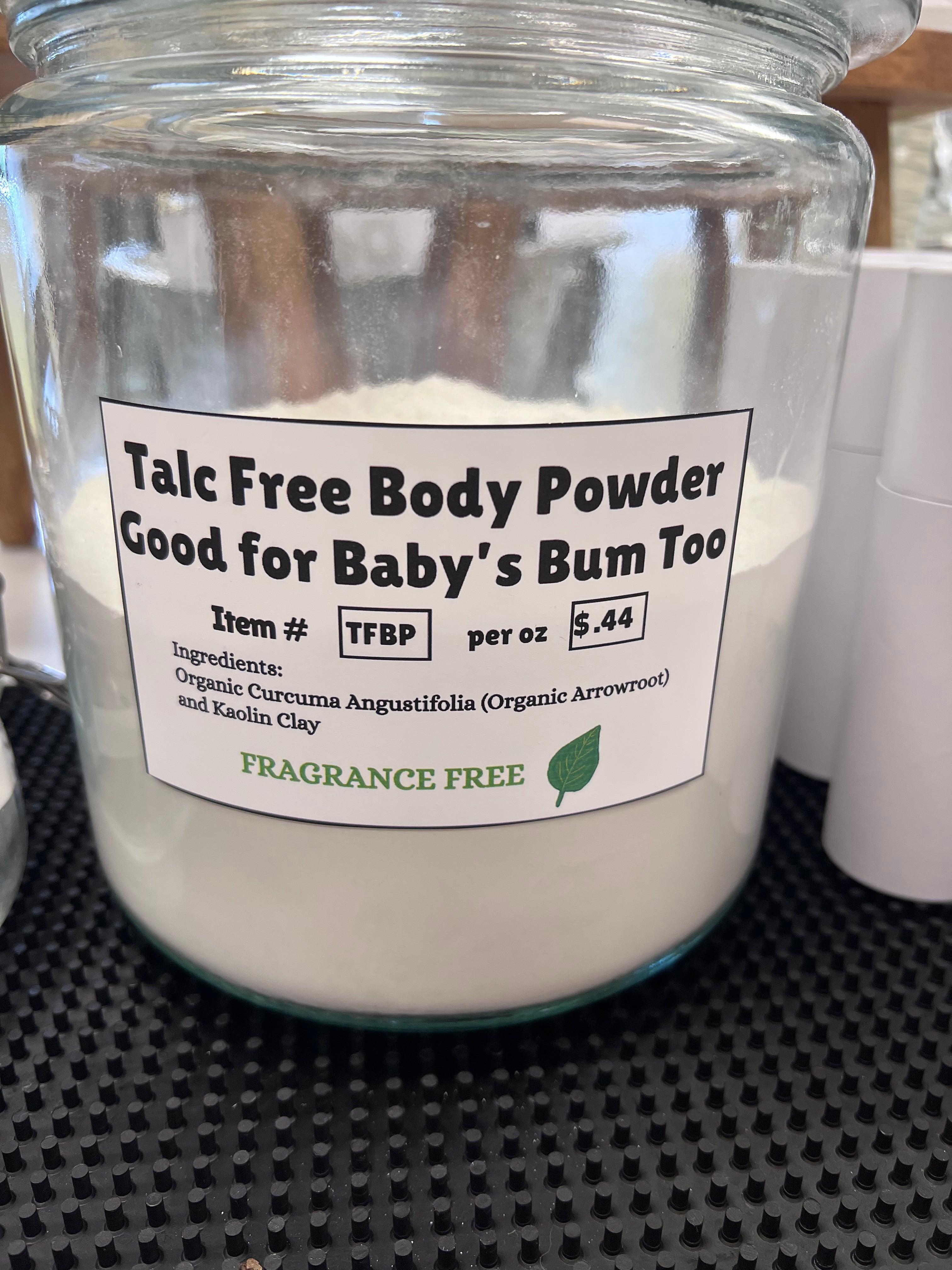 Jar of talc-free body powder with a label on a textured surface