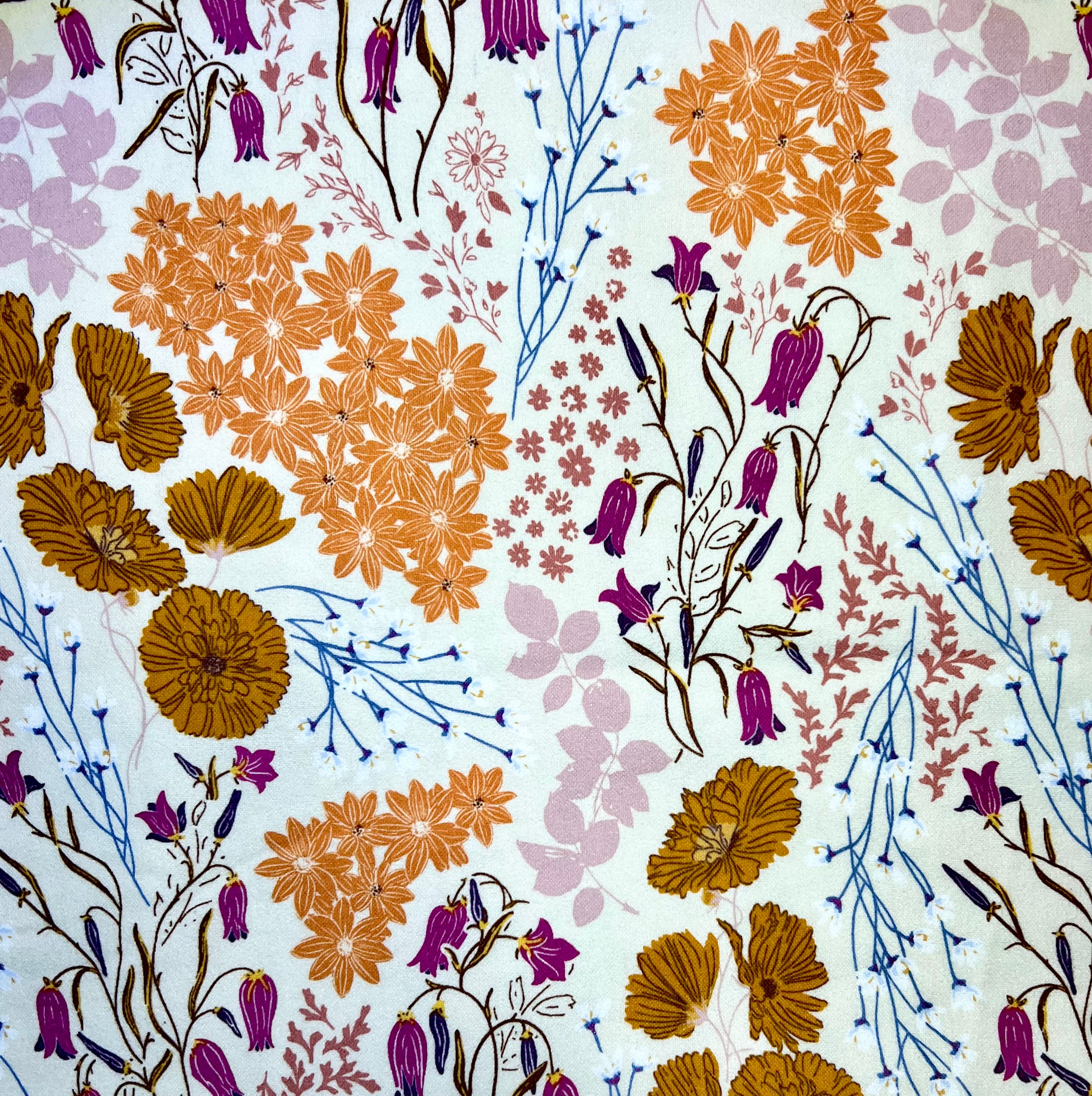 Pattern of various flowers in orange, pink, purple, and brown on a light blue background