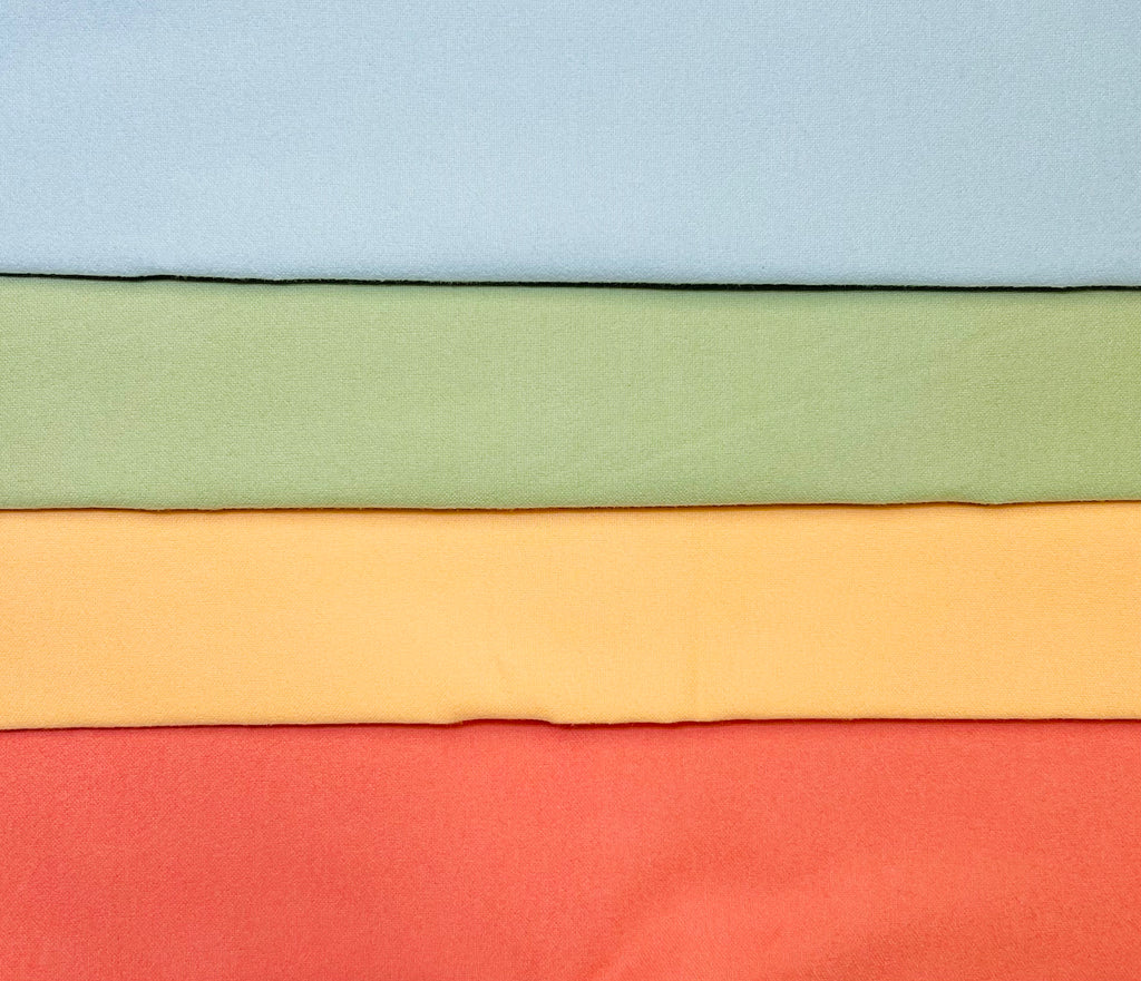 Stack of fabric swatches in light blue, sage green, peach, and coral.