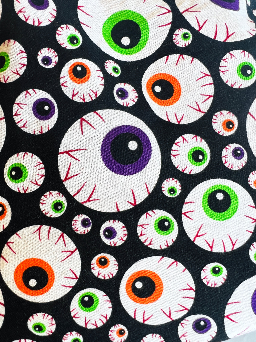 Orange, Green, and Purple BloodShot Eyeball Fabric with a black background. 
