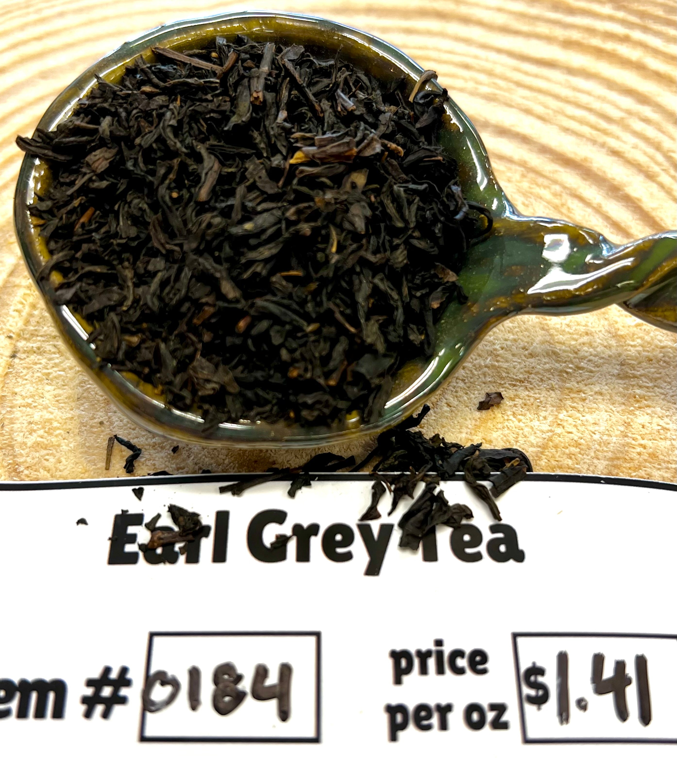 Tea leaves in a spoon with 'Earl Grey Tea' label on a wooden background
