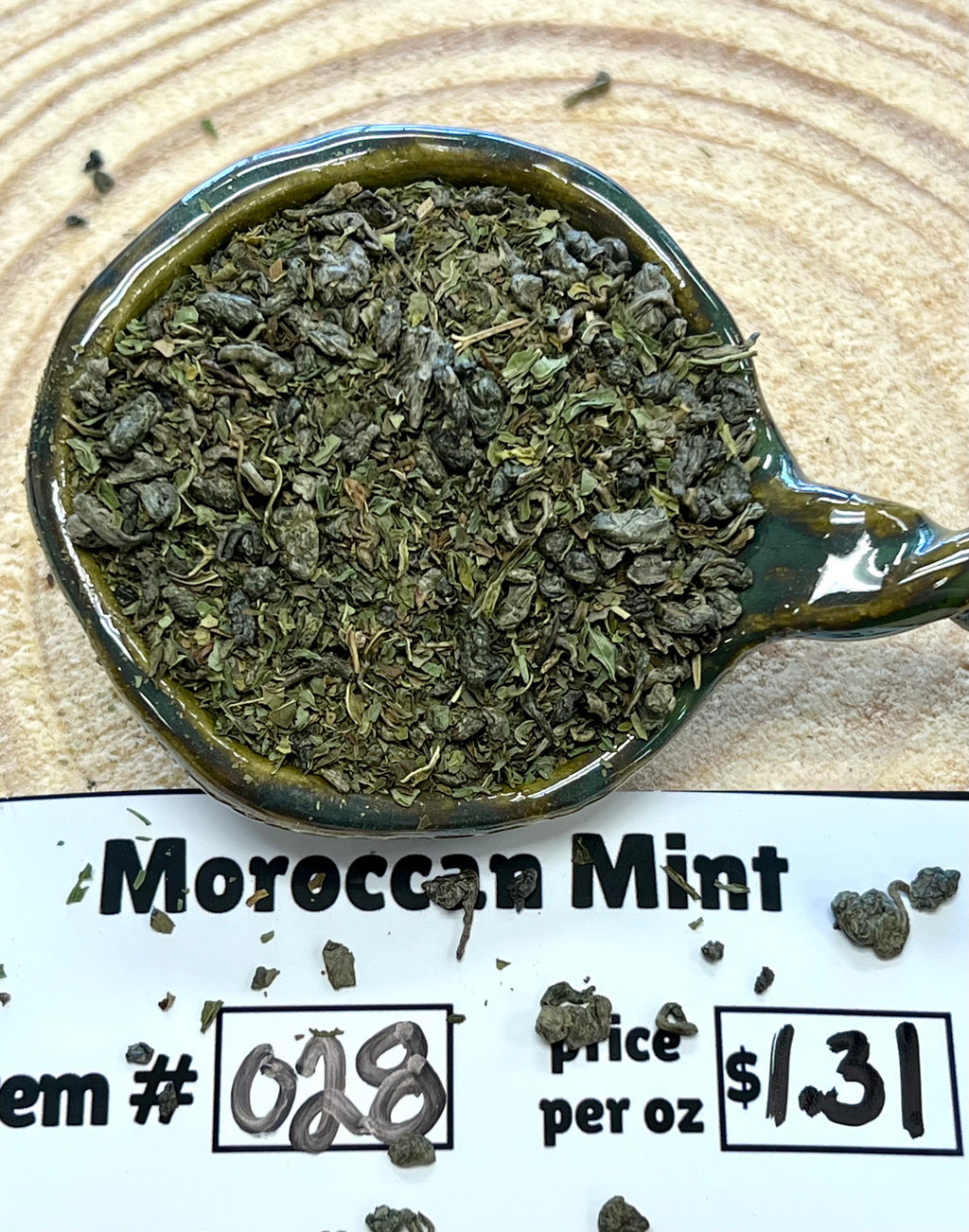 Moroccan mint in a teabag with price and item number information on a wooden surface.