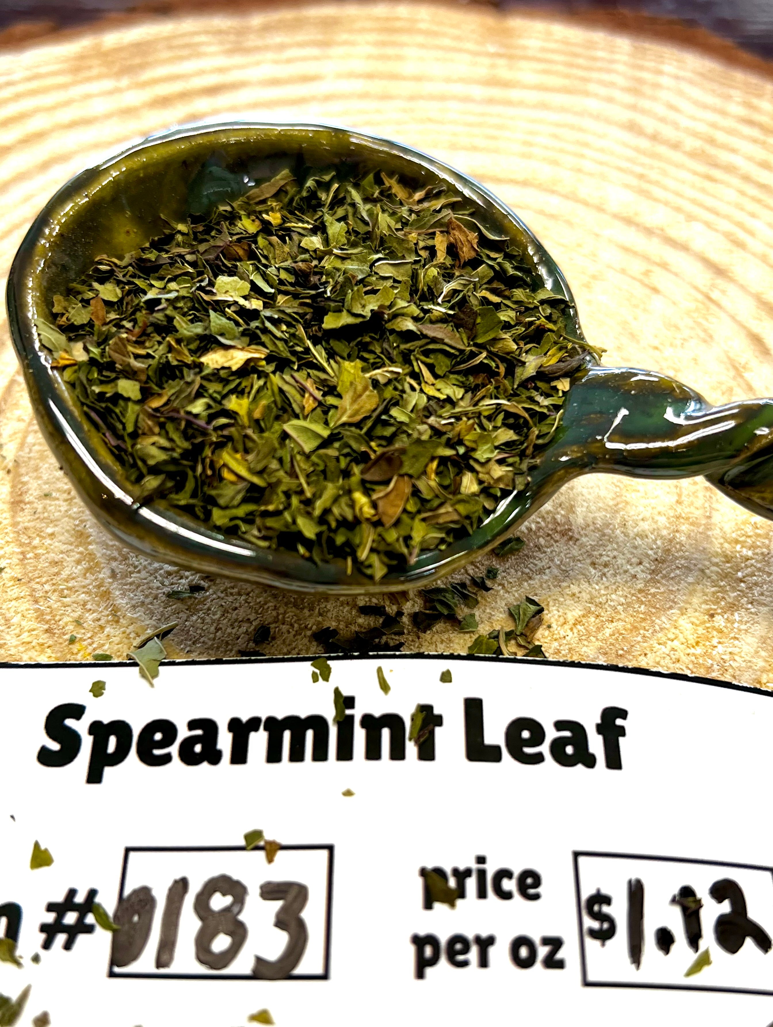 Spoonful of spearmint leaf with a price label on a wooden surface