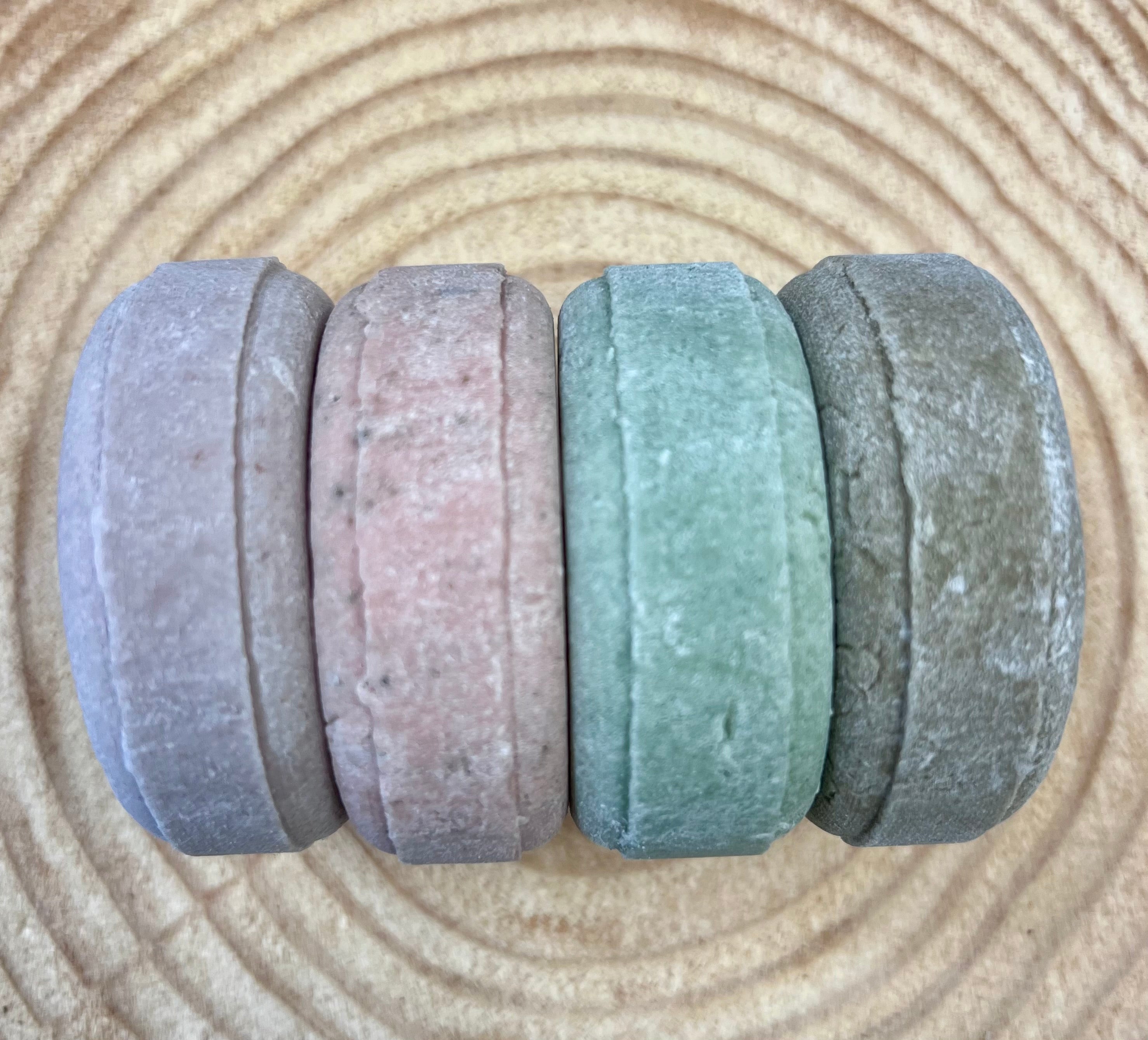Four shampoo bars of different colors on a wood surface