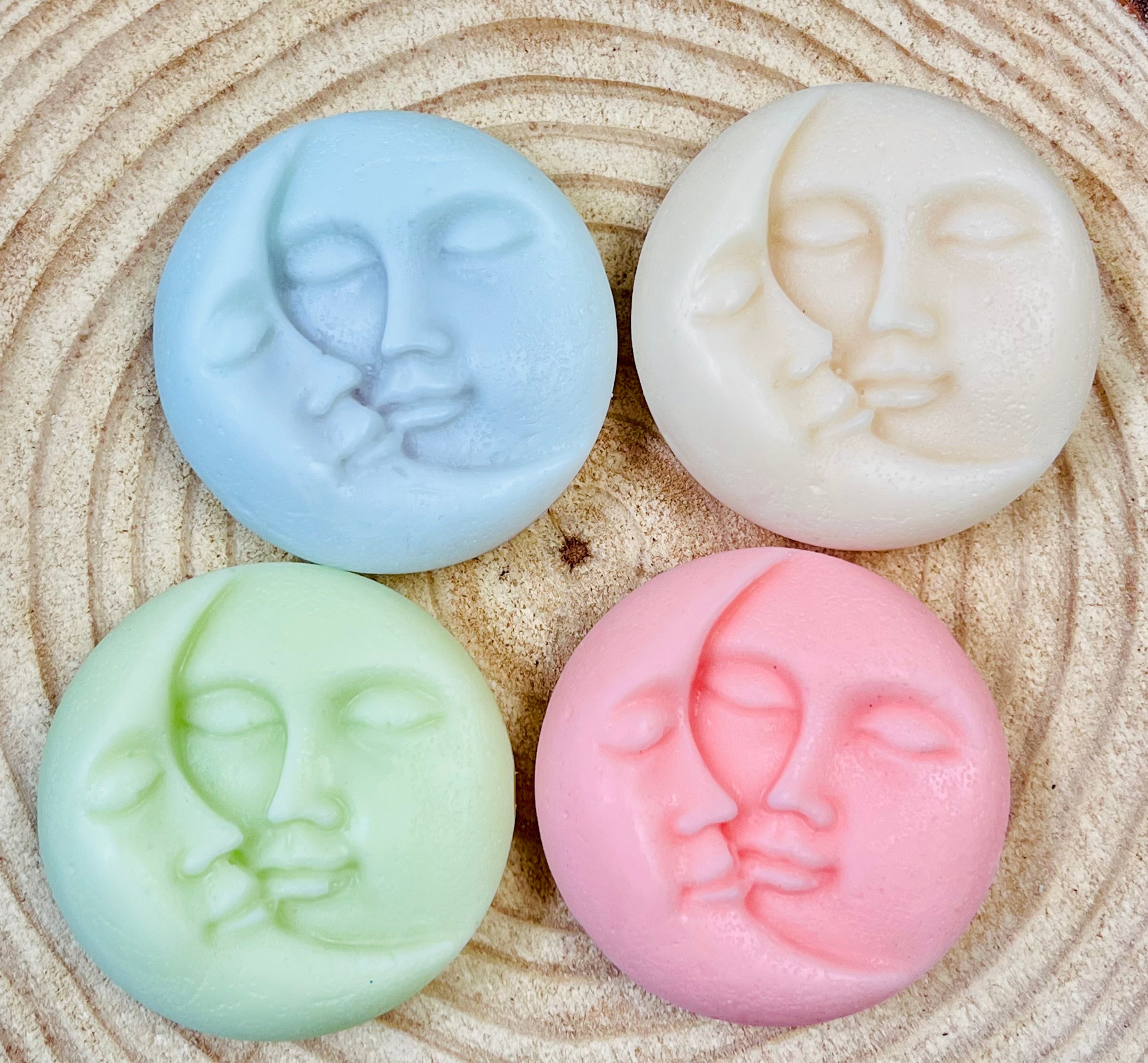 Four colorful conditioner bars with moon & Sun face designs on a wood surface.