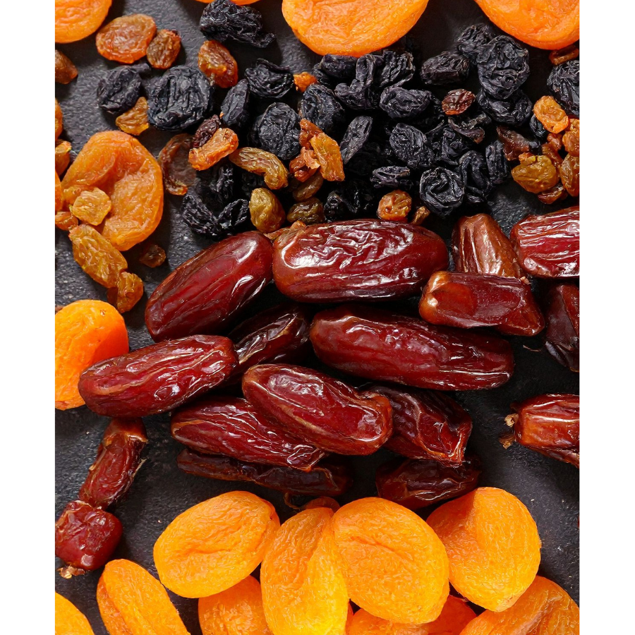 Assorted dried fruits including raisins and apricots on a dark surface