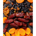 Assorted dried fruits including raisins and apricots on a dark surface