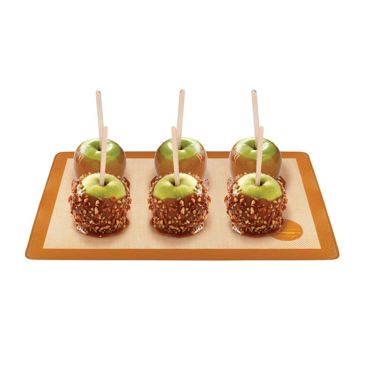 Four caramel apples on a silicone baking mat with a white background.