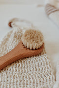 Wooden scrub brush with natural bristles on a textured surface