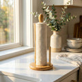 Paper towel holder on a kitchen counter with a vase and plants in the background