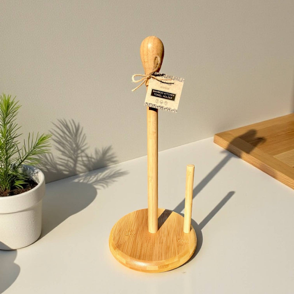 Wooden paper towel holder with a plant and cutting board in the background