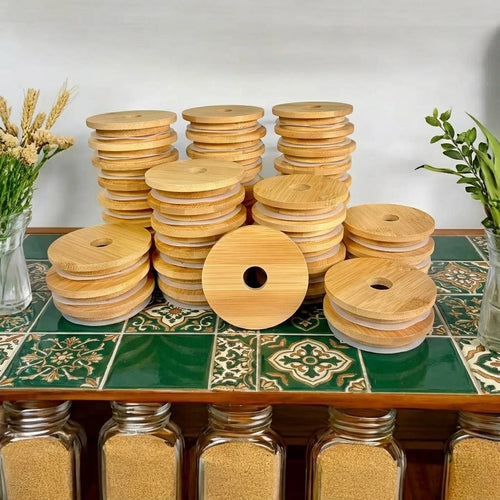 Stacks of round bamboo spool covers with a central hole, displayed on a green tiled table with decorative plants and glass jars in the background.