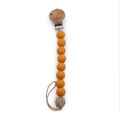 Orange silicone beaded pacifier clip with wooden accents on a white background