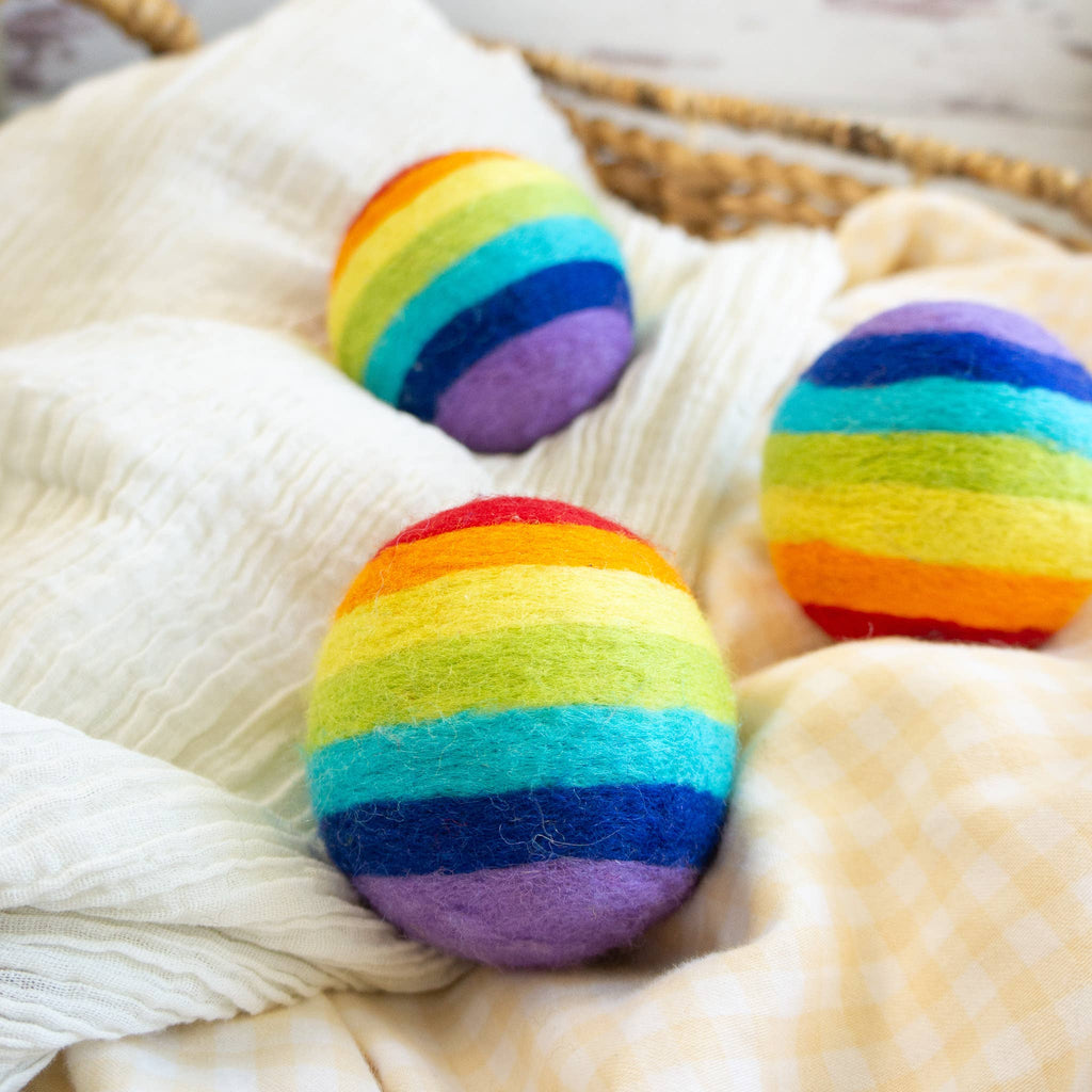 Rainbow-colored rainbow-colored wool dryer ball on a white surface with a basket in the background