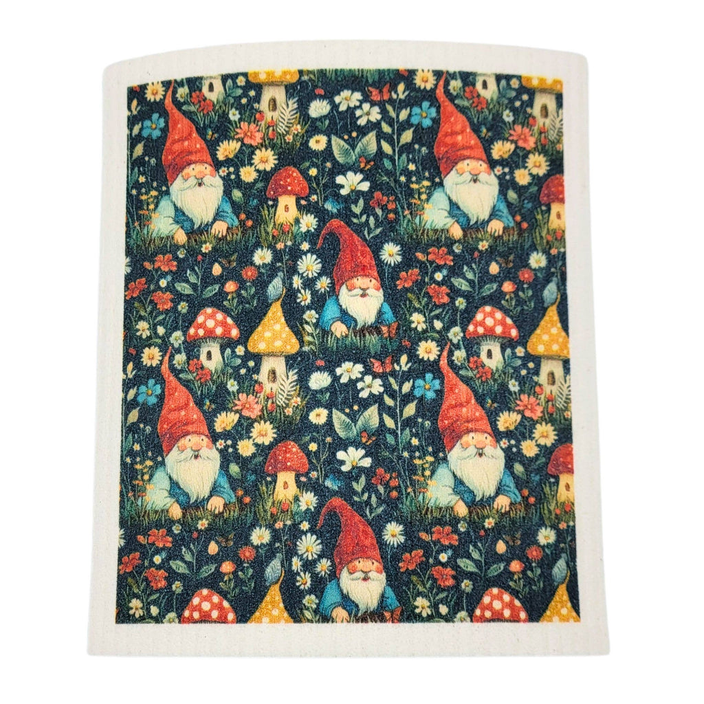 A square fabric item, likely a tea towel or napkin, featuring a whimsical garden gnome pattern on a dark navy background. The pattern includes red-hatted gnomes, red and yellow mushrooms, and small houses among white and yellow flowers.